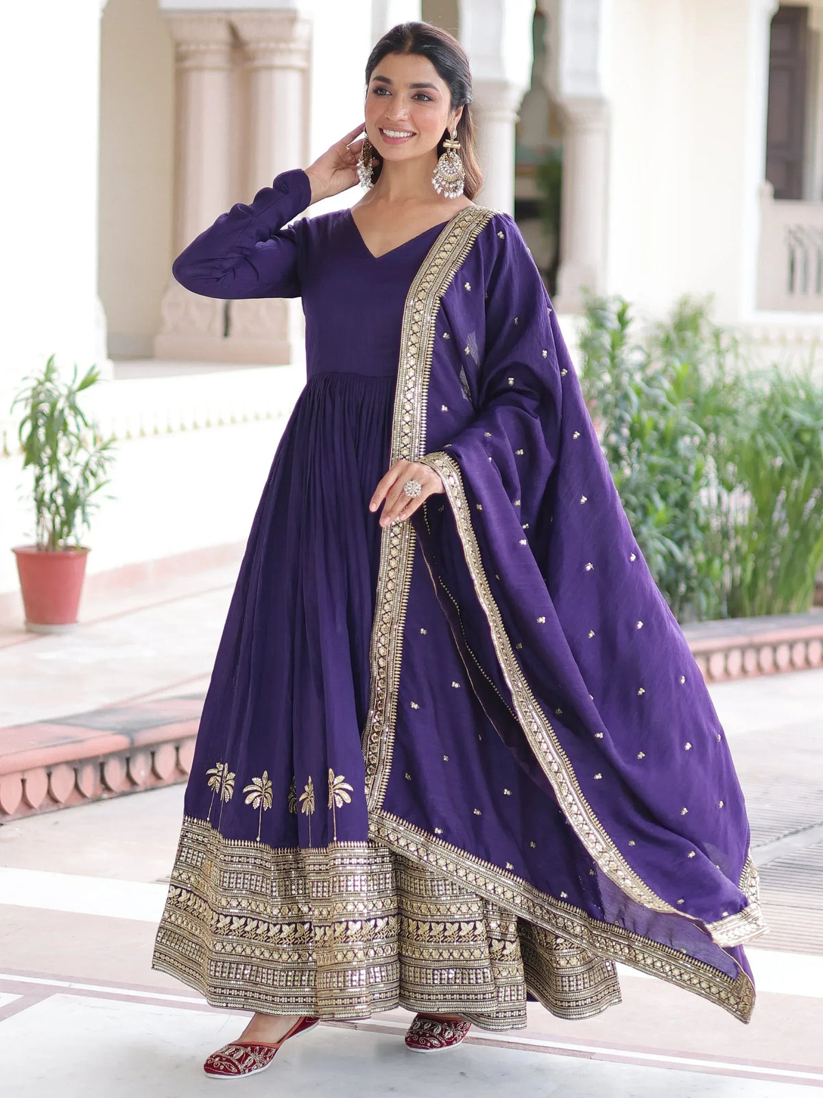Woman wearing a purple Anarkali suit with gold zari embroidery and a matching dupatta.