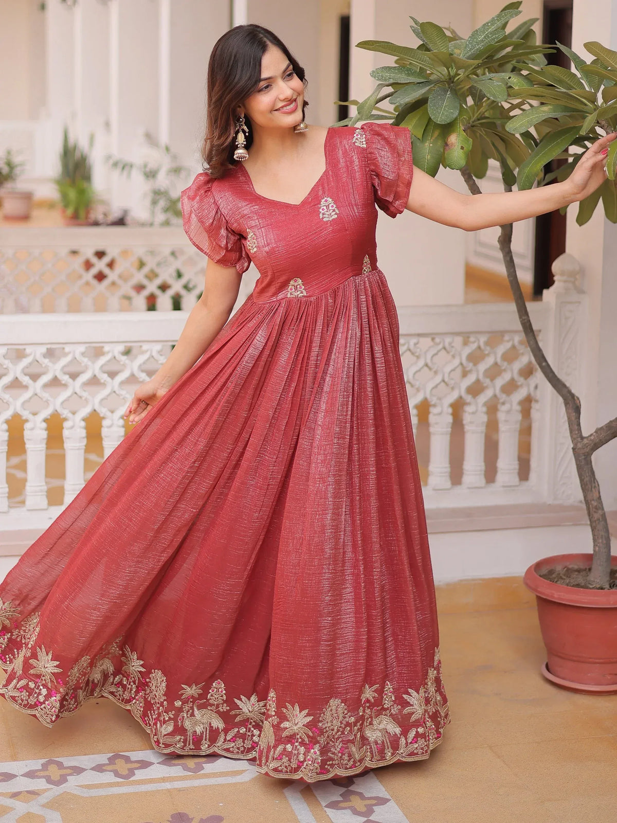 Woman wearing a red embroidered ethnic gown with puff sleeves standing in a courtyard