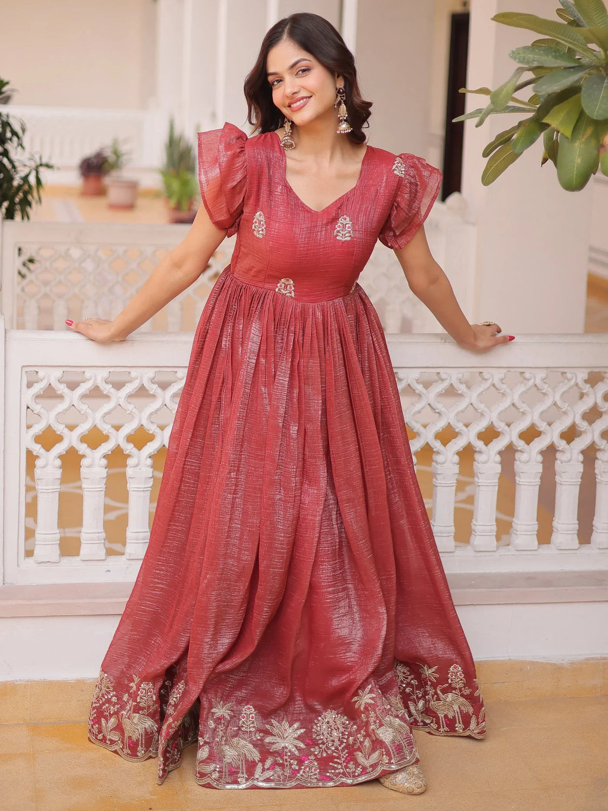 Woman wearing a maroon embroidered ethnic gown with ruffled sleeves
