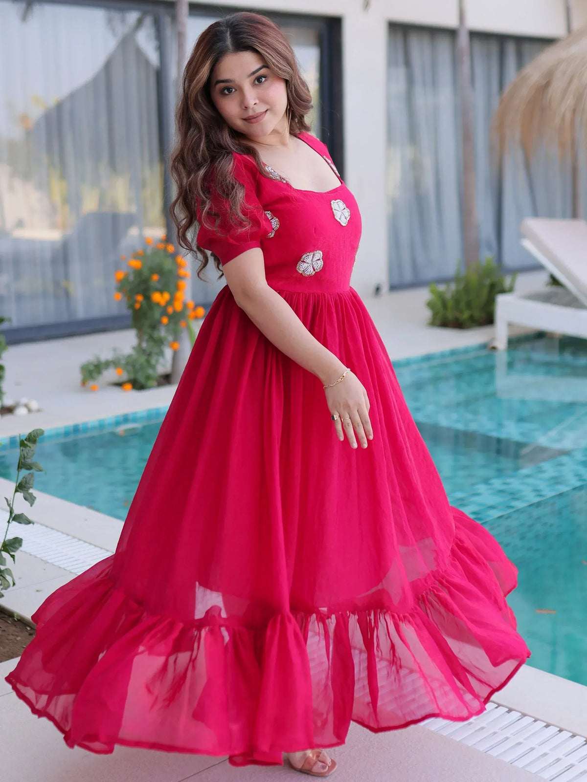 Vibrant red ethnic gown with floral embroidery, perfect for festive occasions, styled by poolside.