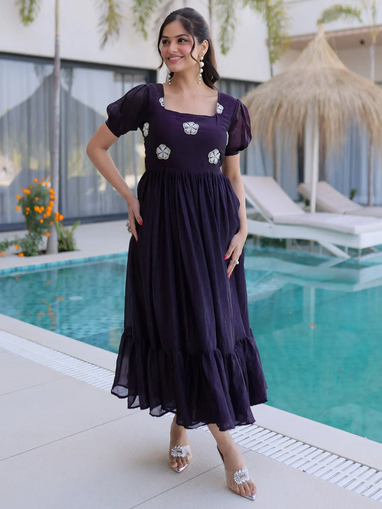 Purple ethnic gown with floral embellishments, puff sleeves, and ruffle hem, styled by poolside