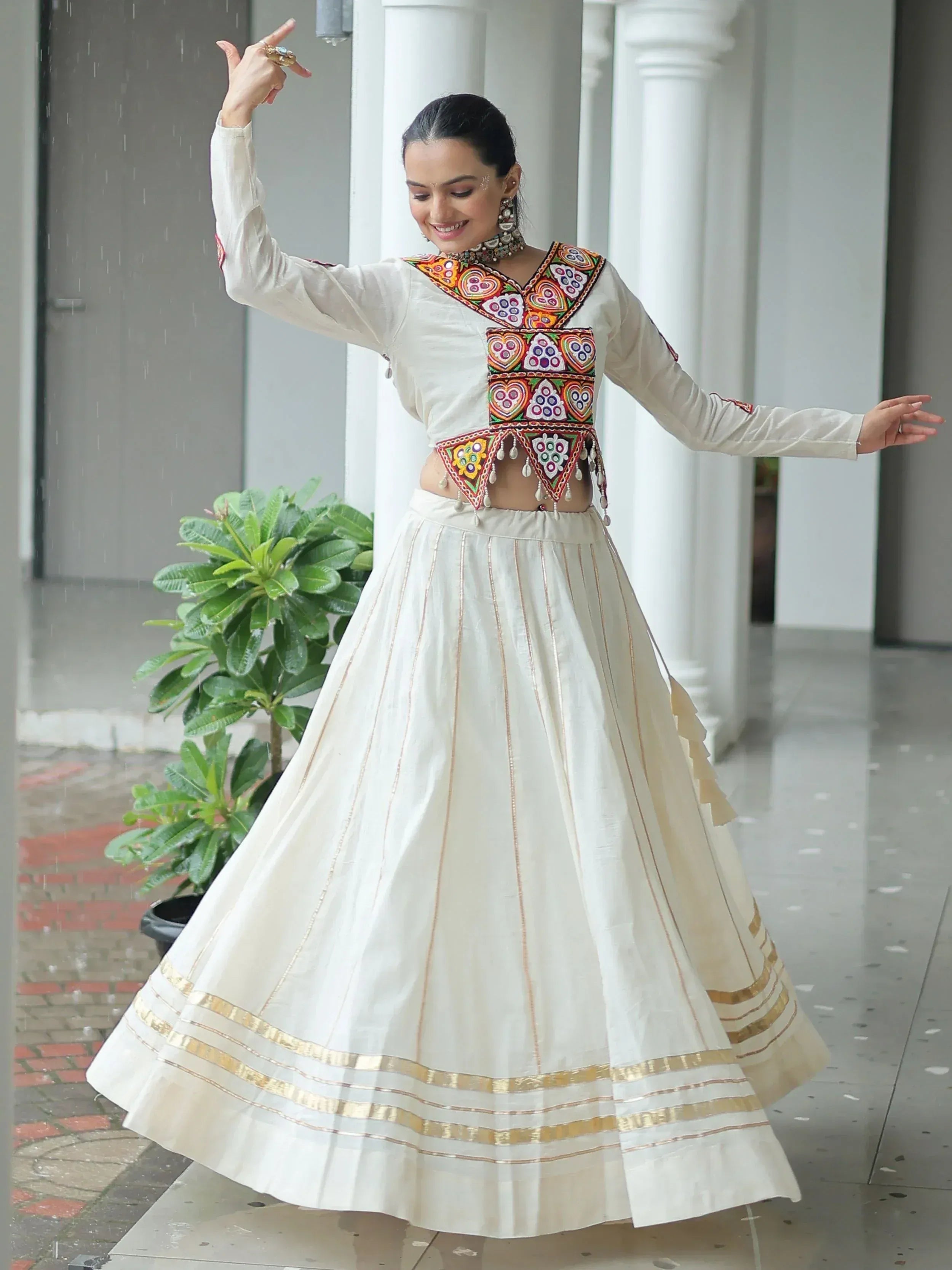 Woman in white ethnic lehenga choli with colorful embroidery dancing in rain