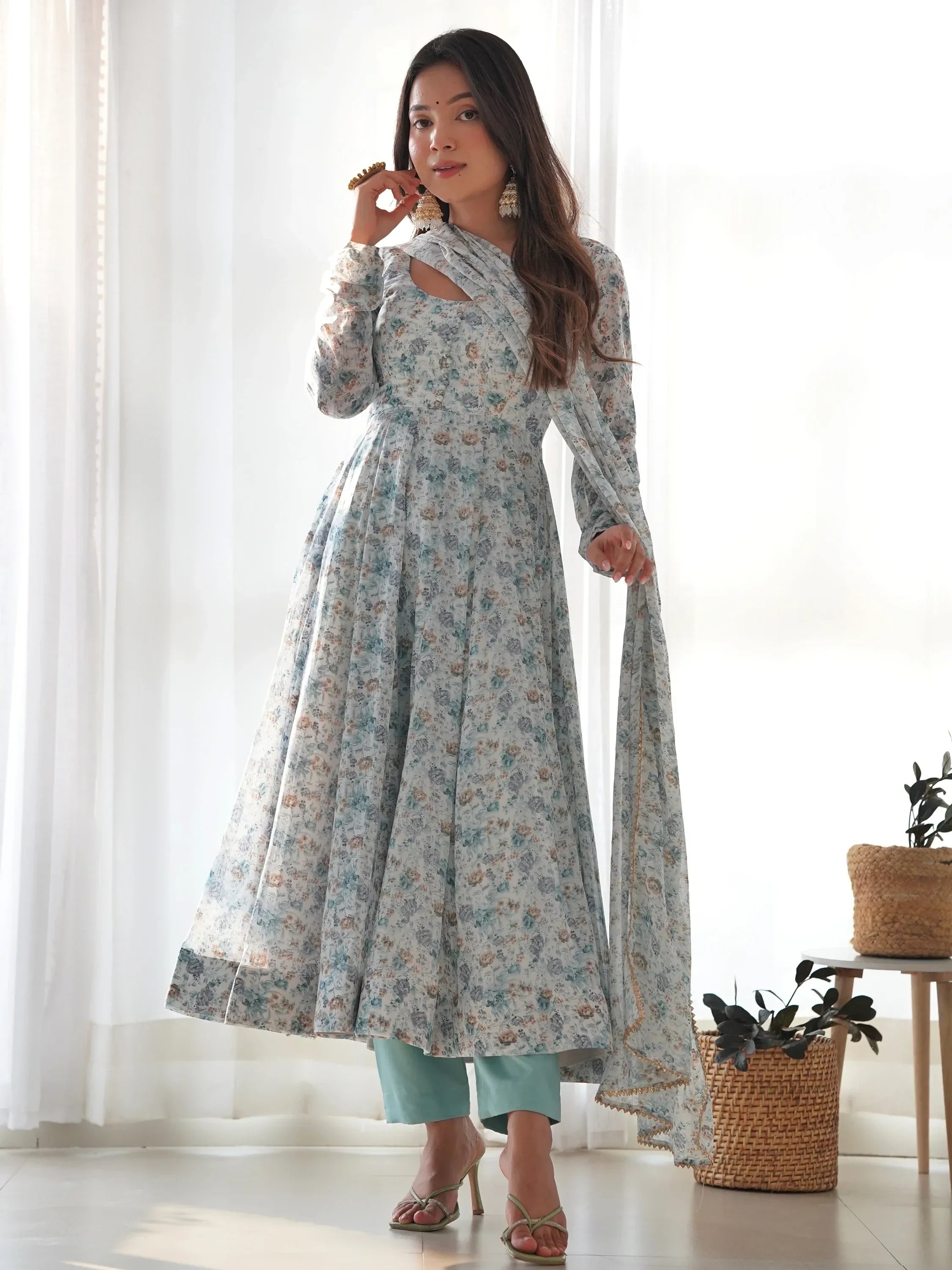 Woman wearing a light blue floral Anarkali suit with dupatta, ethnic Indian attire indoors