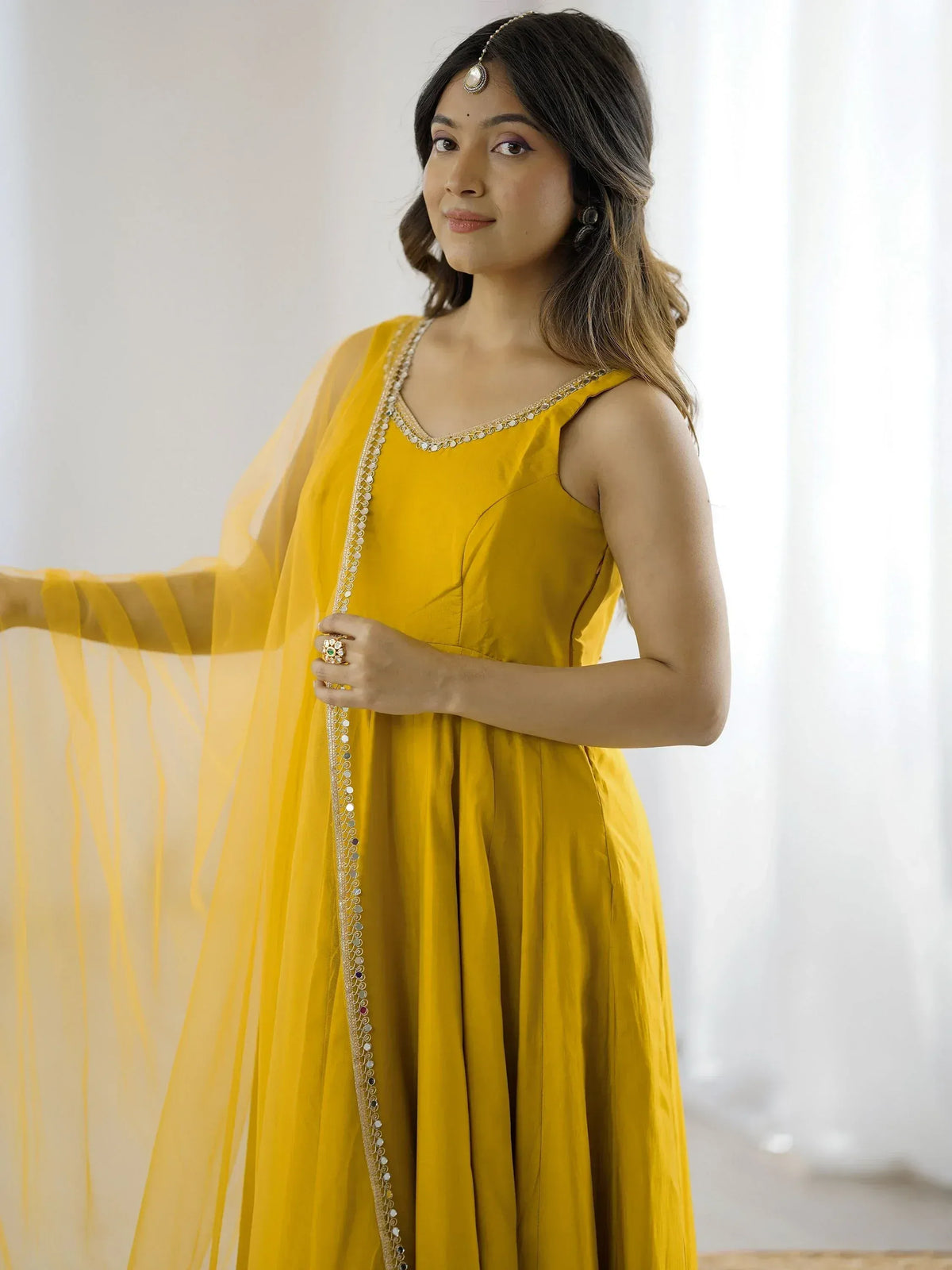 Yellow ethnic gown with mirror work and sheer dupatta, perfect for Indian occasions