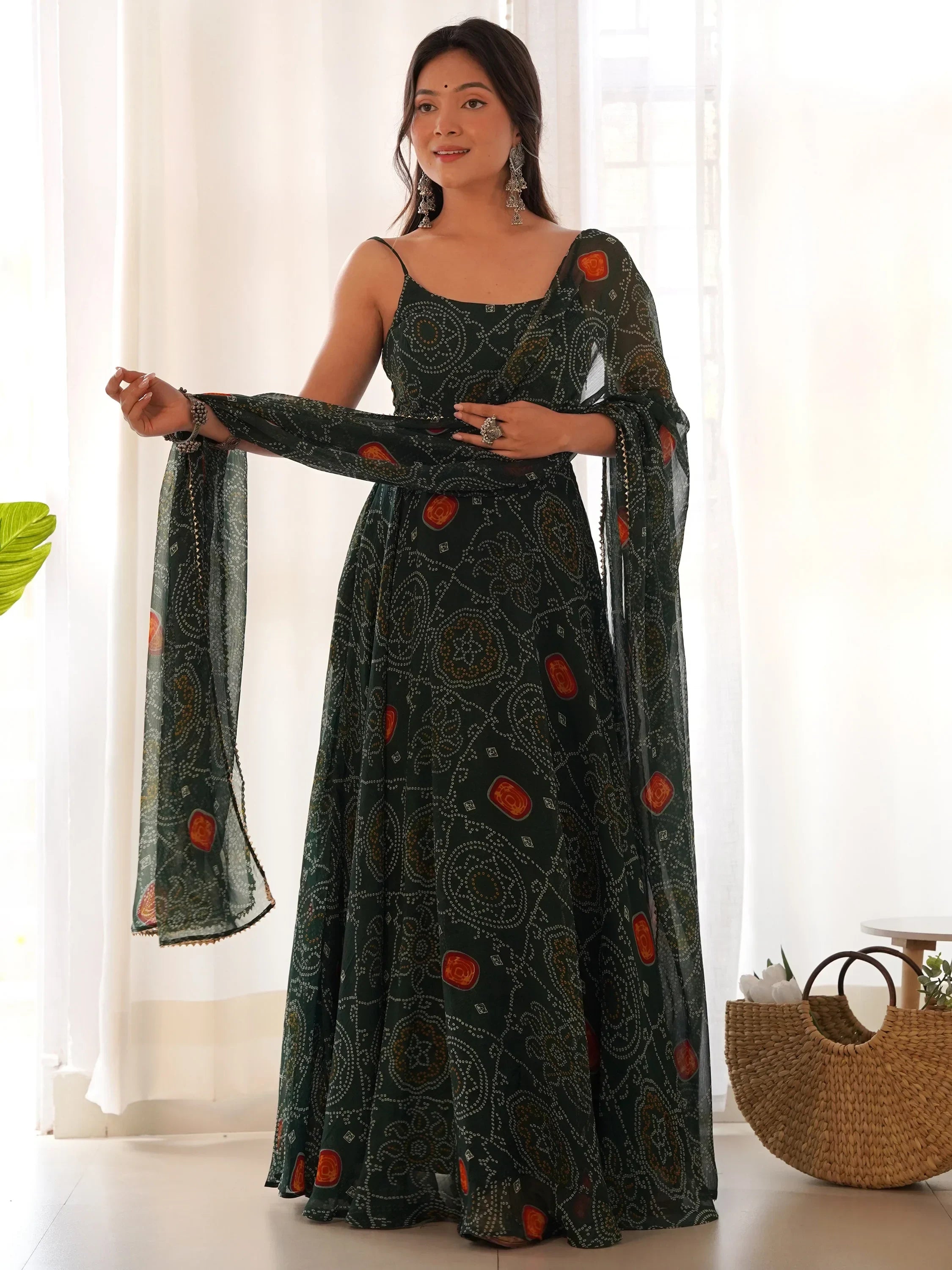 Woman in green printed ethnic gown with dupatta, wearing statement jewelry, indoor setting