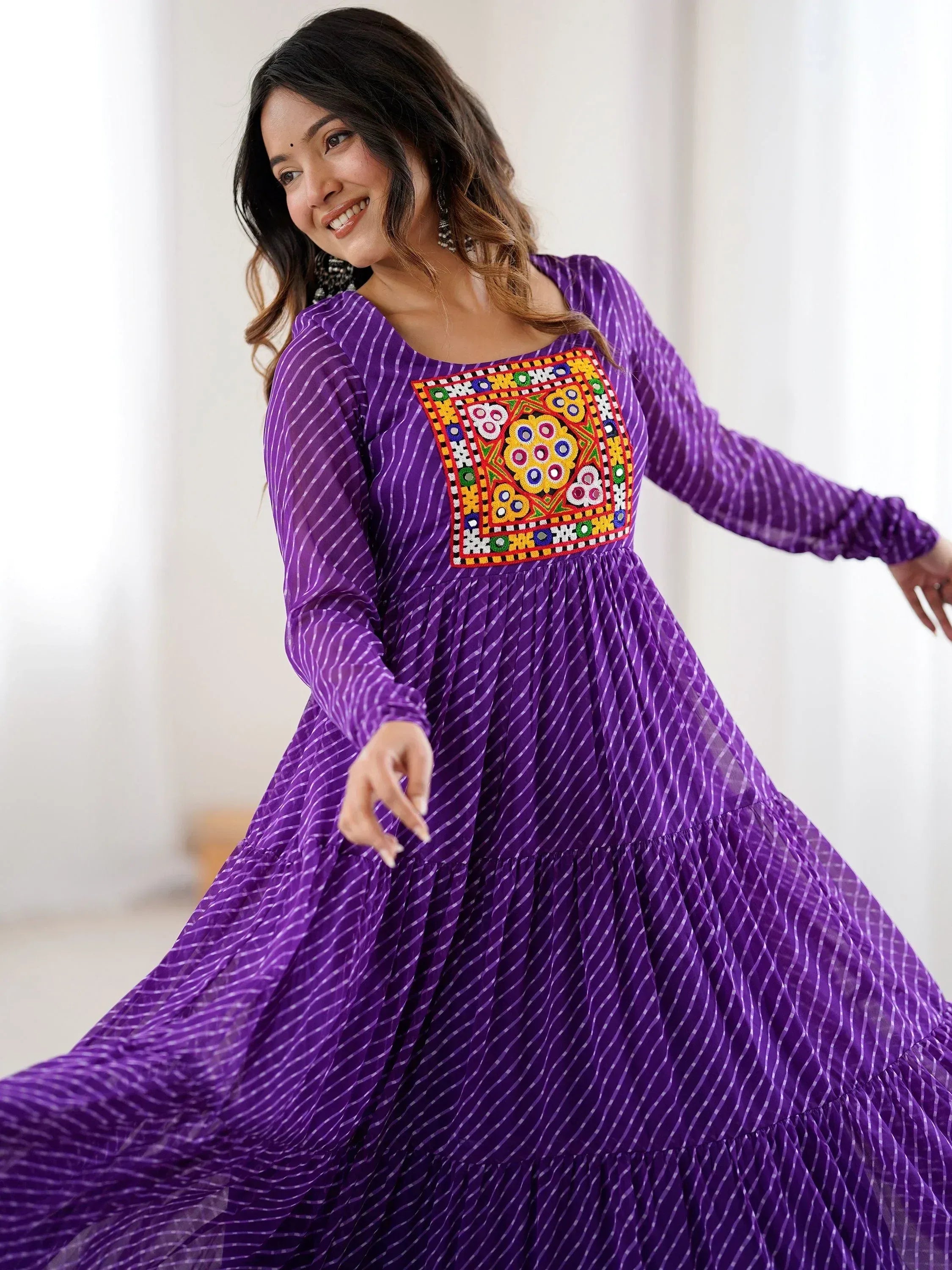 Purple ethnic gown with colorful mirror work and striped print, perfect for festive occasions