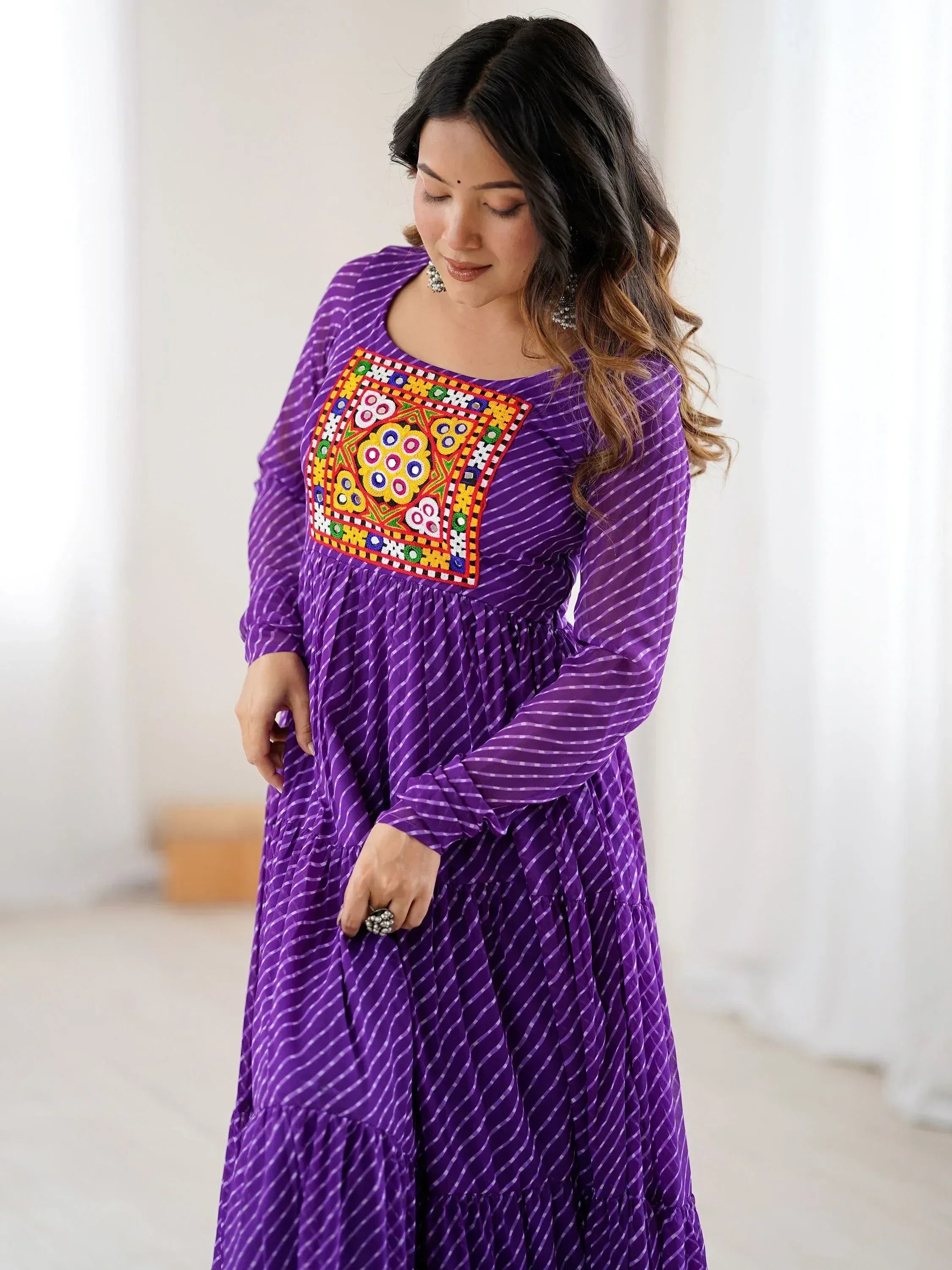 Purple ethnic gown with colorful mirror work and striped print, perfect for Indian festive occasions