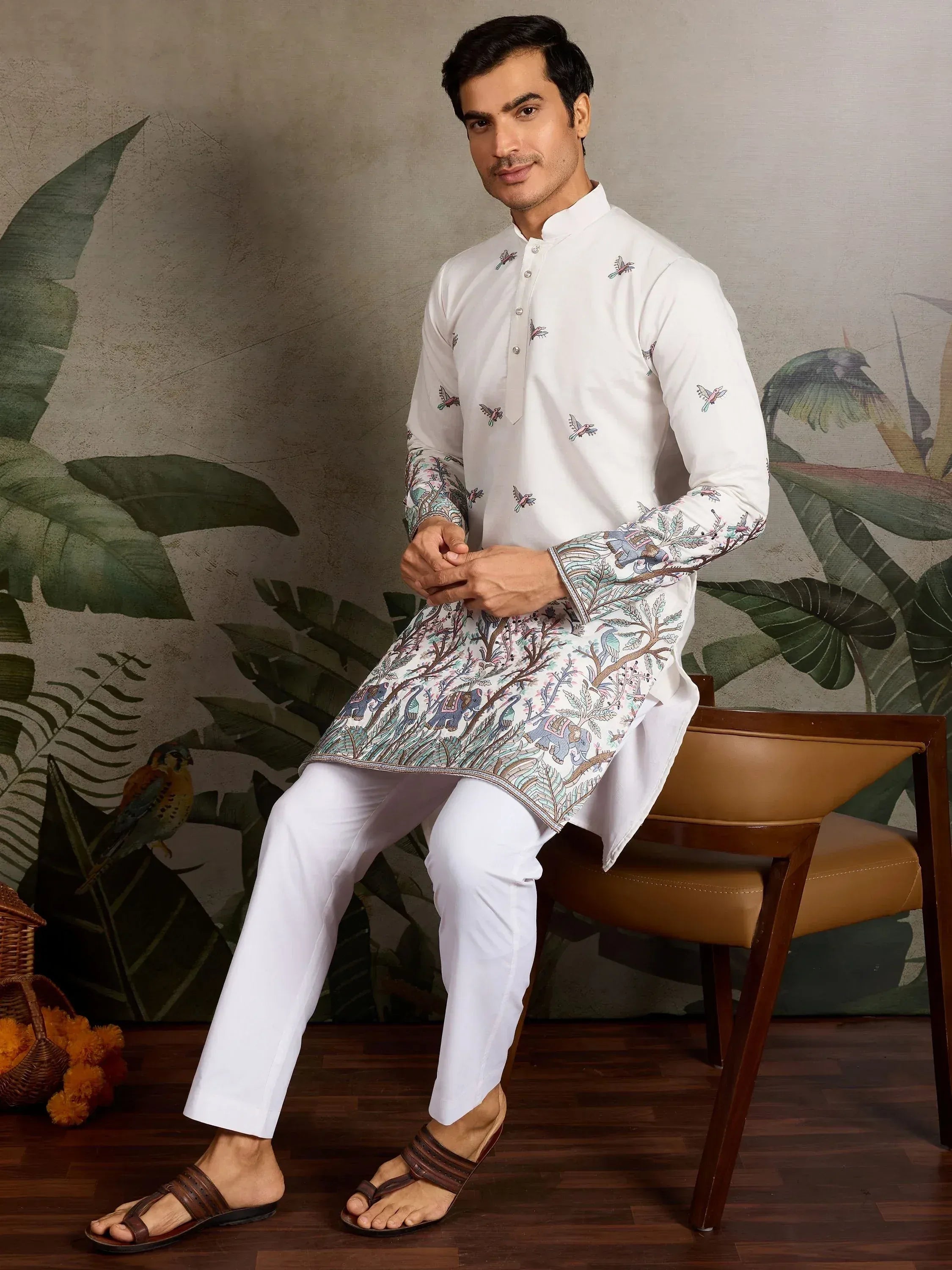 White embroidered kurta with elephant and bird motifs, paired with churidar pants for men's ethnic wear
