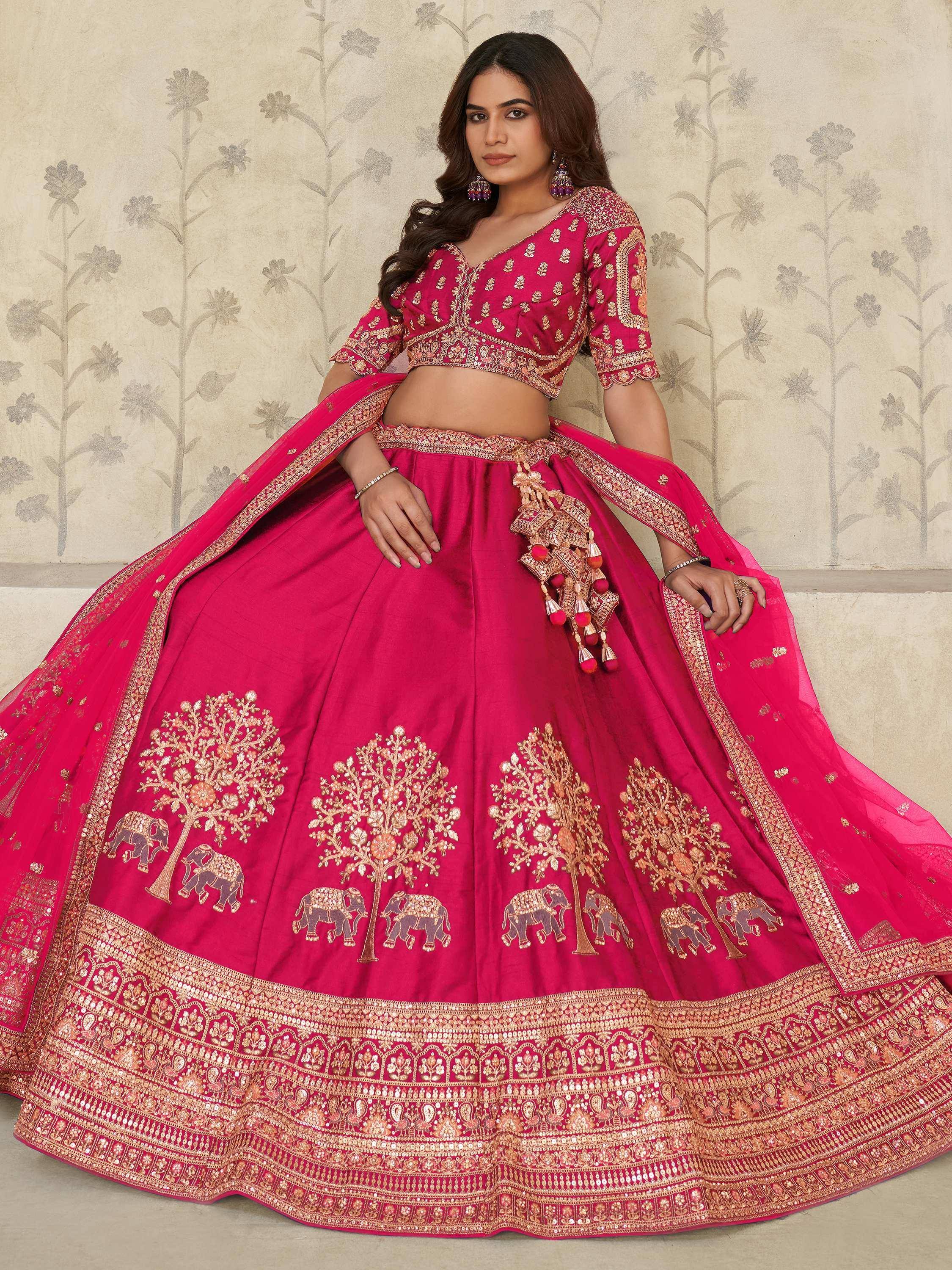 Pink designer lehenga choli with gold embroidery, elephant and tree motifs, perfect for Indian weddings and festivals.