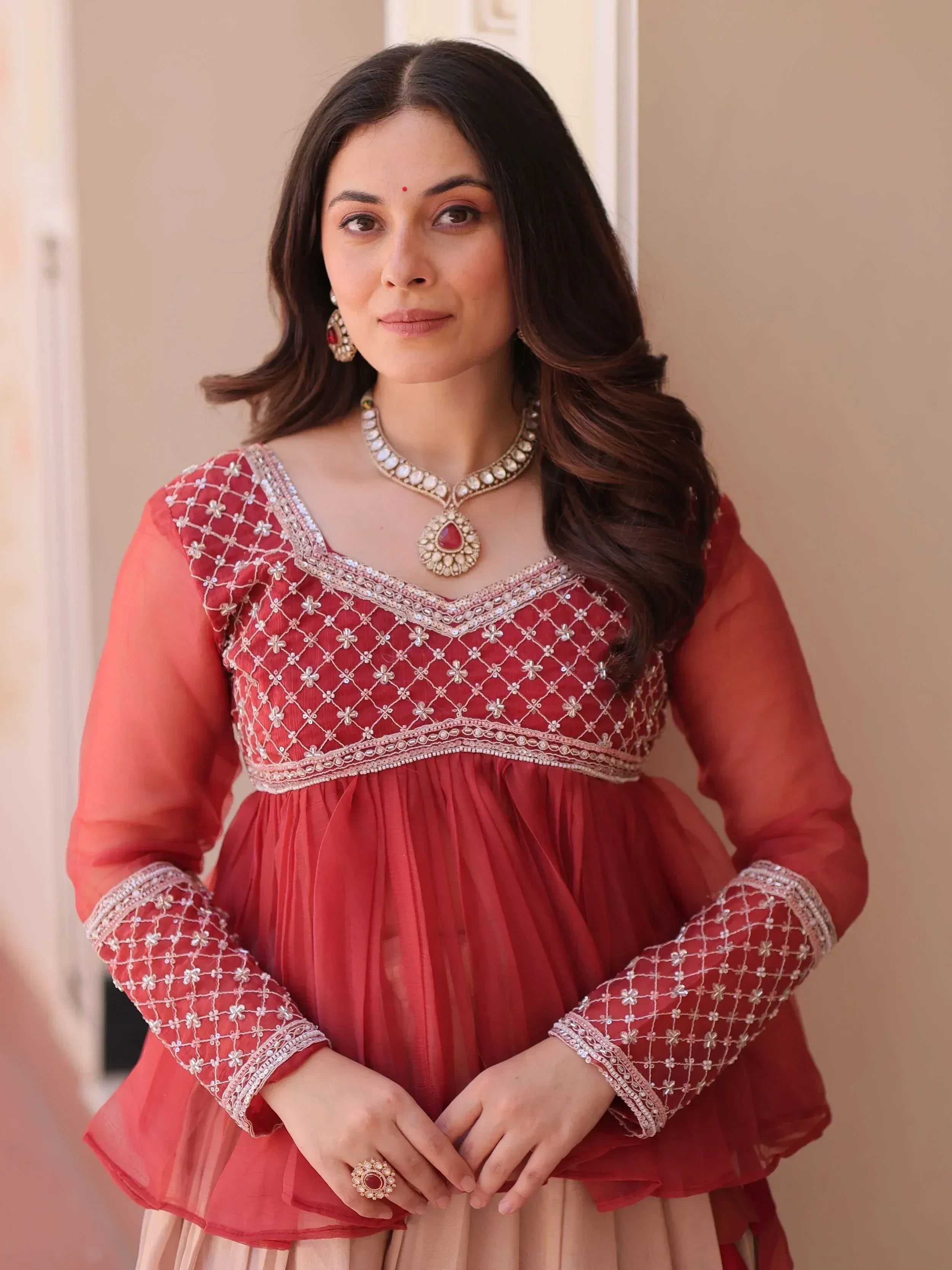 Woman in red embroidered ethnic gown with gold jewelry, perfect for Indian festive occasions