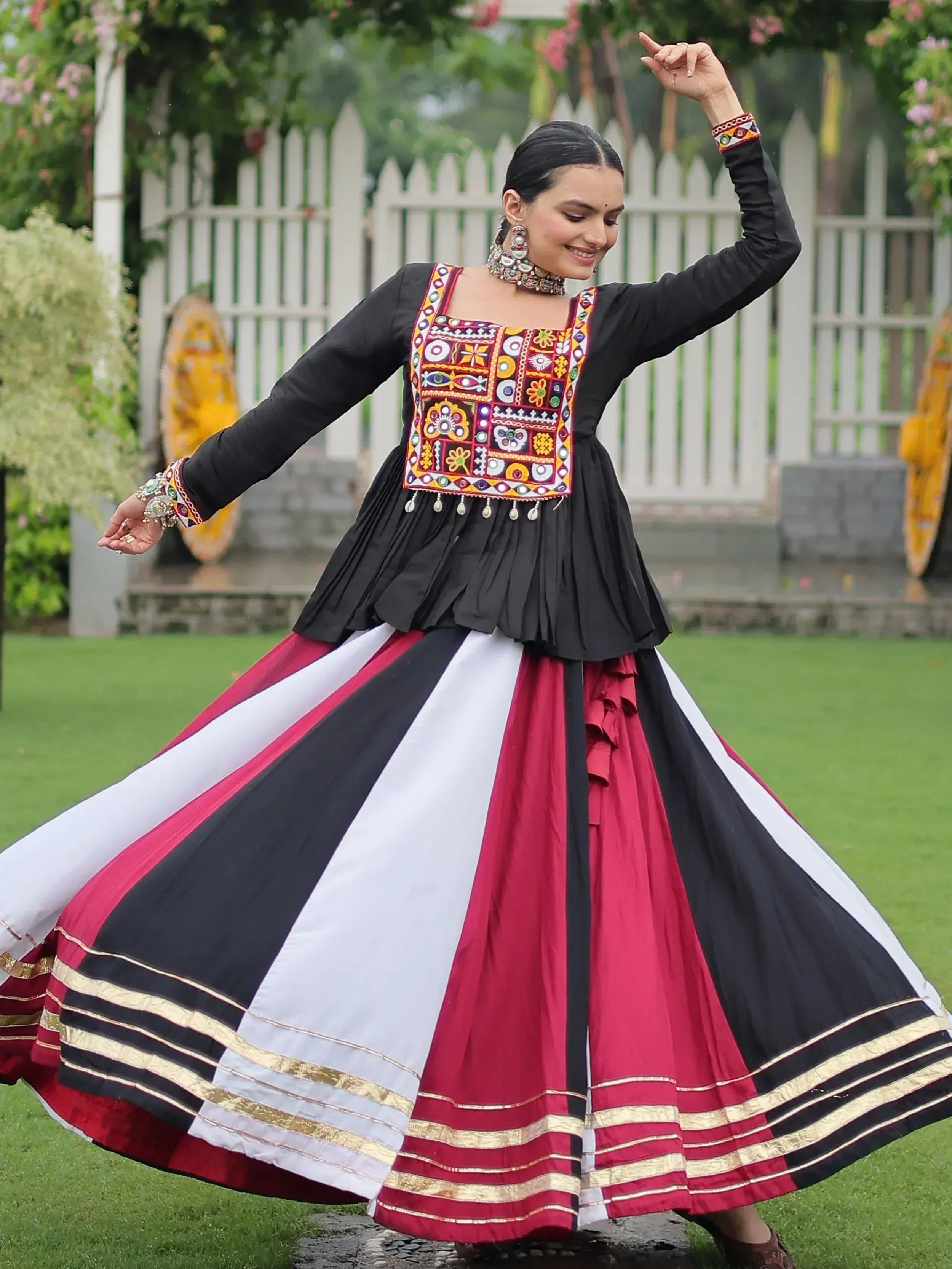Woman in black top with colorful embroidery and striped red-white-black skirt, dancing outdoors