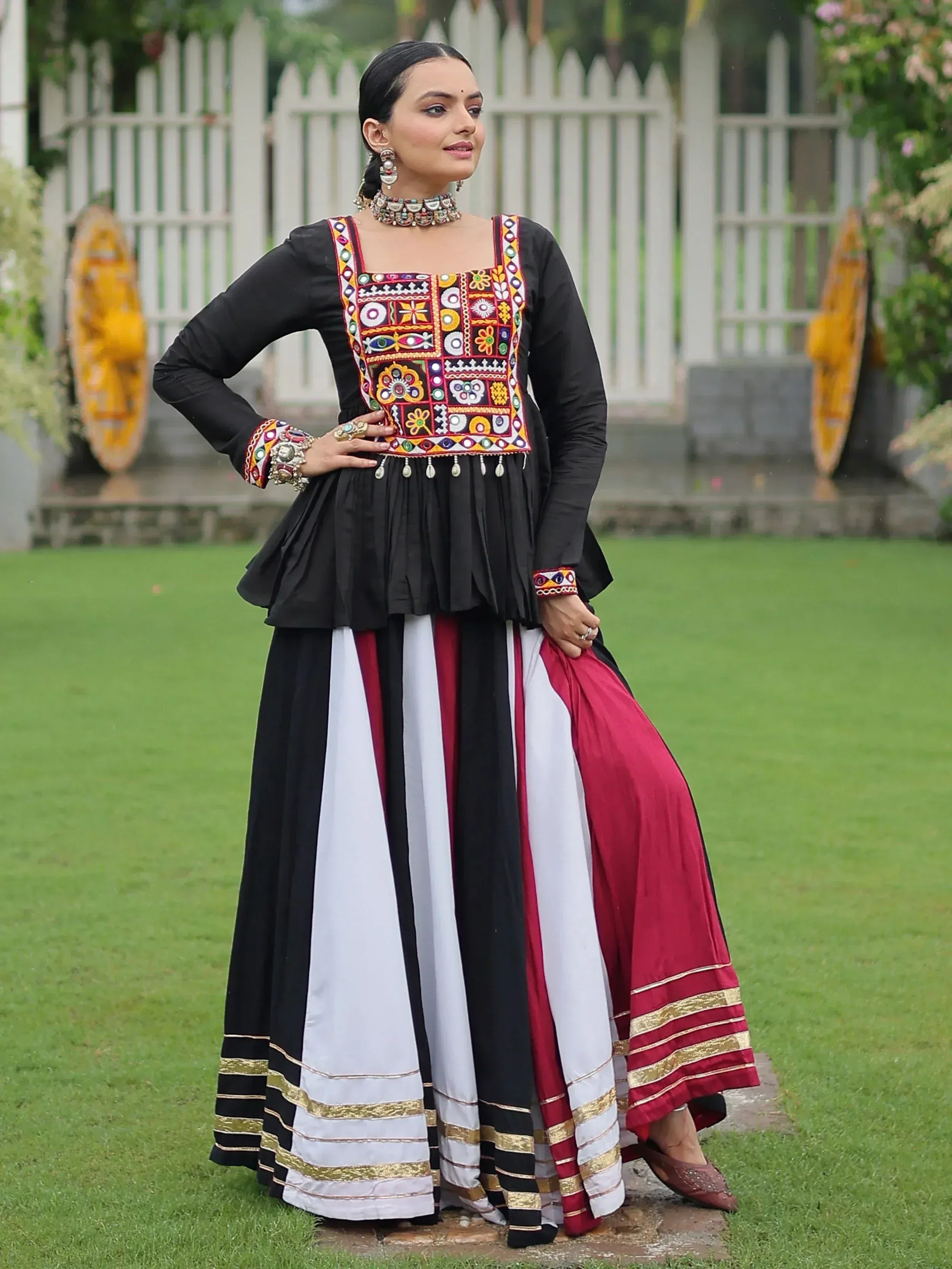 Woman in black embroidered top with colorful mirror work and striped skirt, Indian ethnic wear