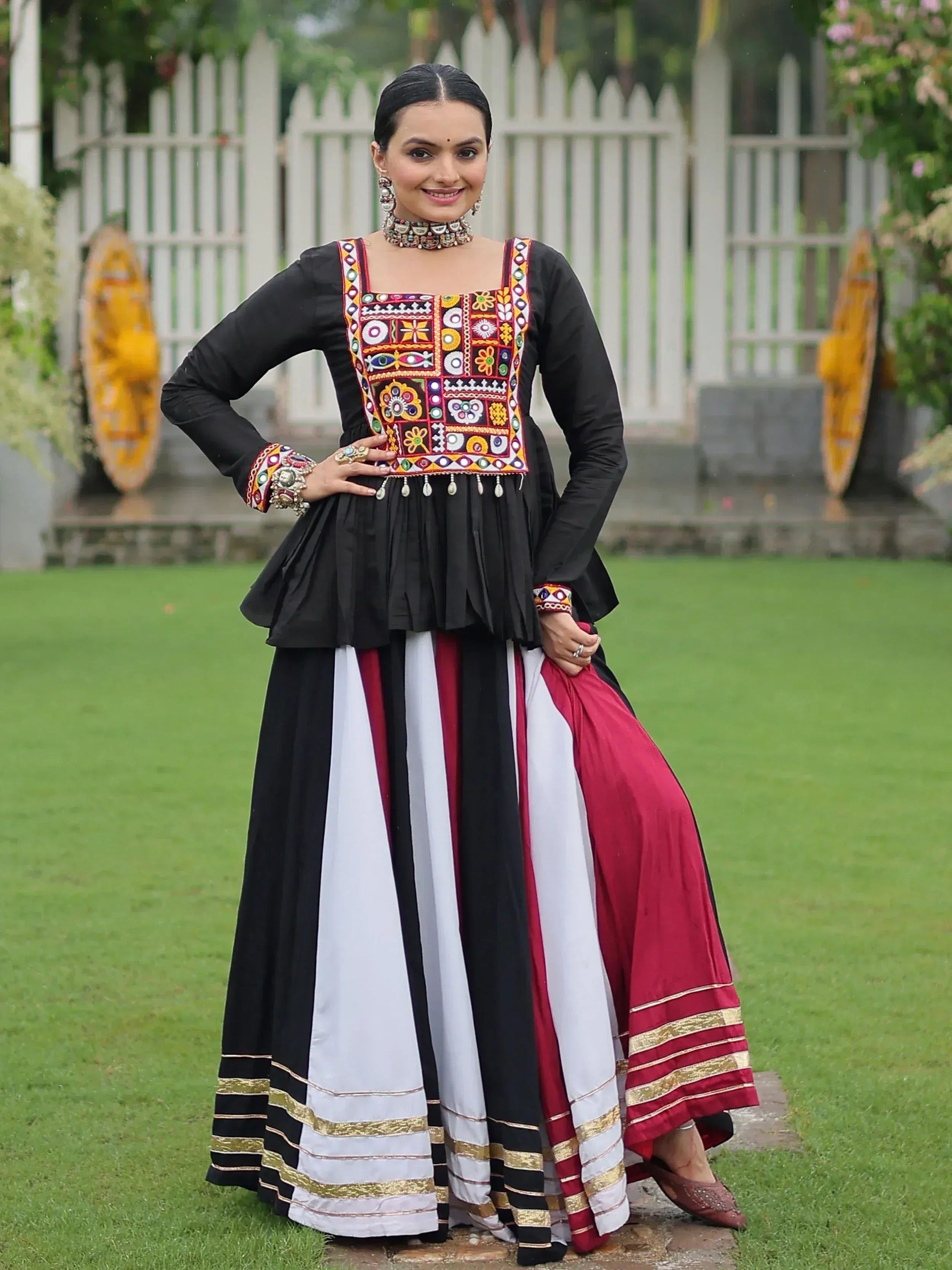 Black embroidered ethnic gown with colorful mirror work, paired with striped skirt, perfect for Indian festive wear.