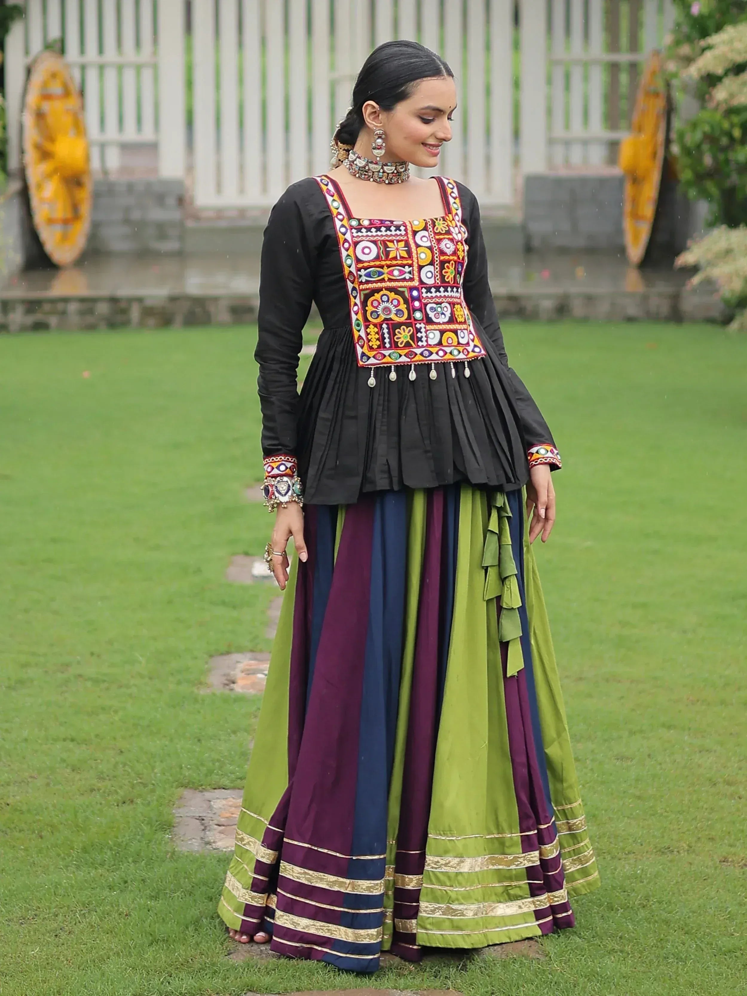 Woman in black embroidered top with colorful striped skirt, traditional Indian ethnic wear