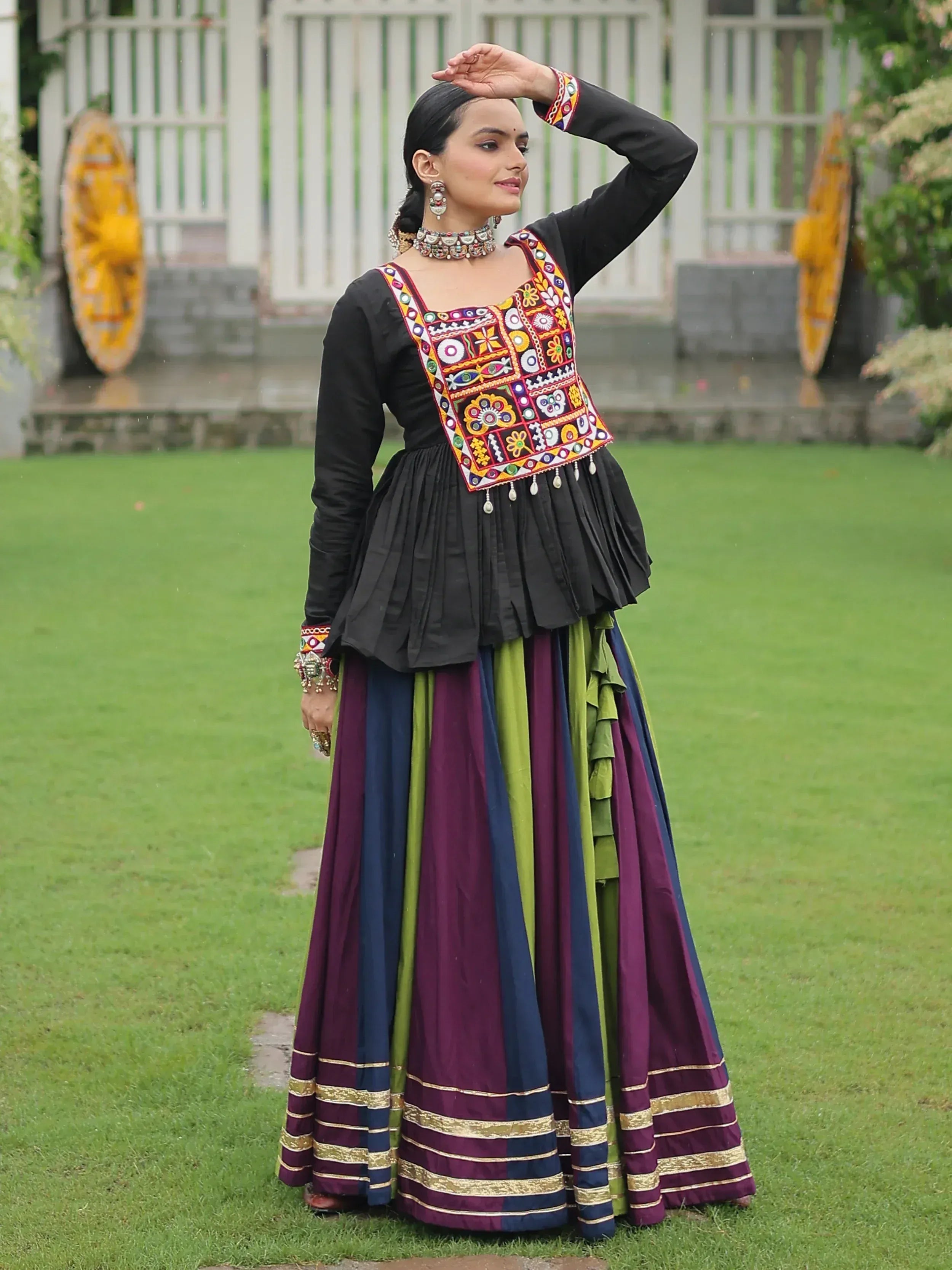 Woman in black embroidered top with colorful patchwork and multi-color pleated skirt, traditional Indian ethnic wear