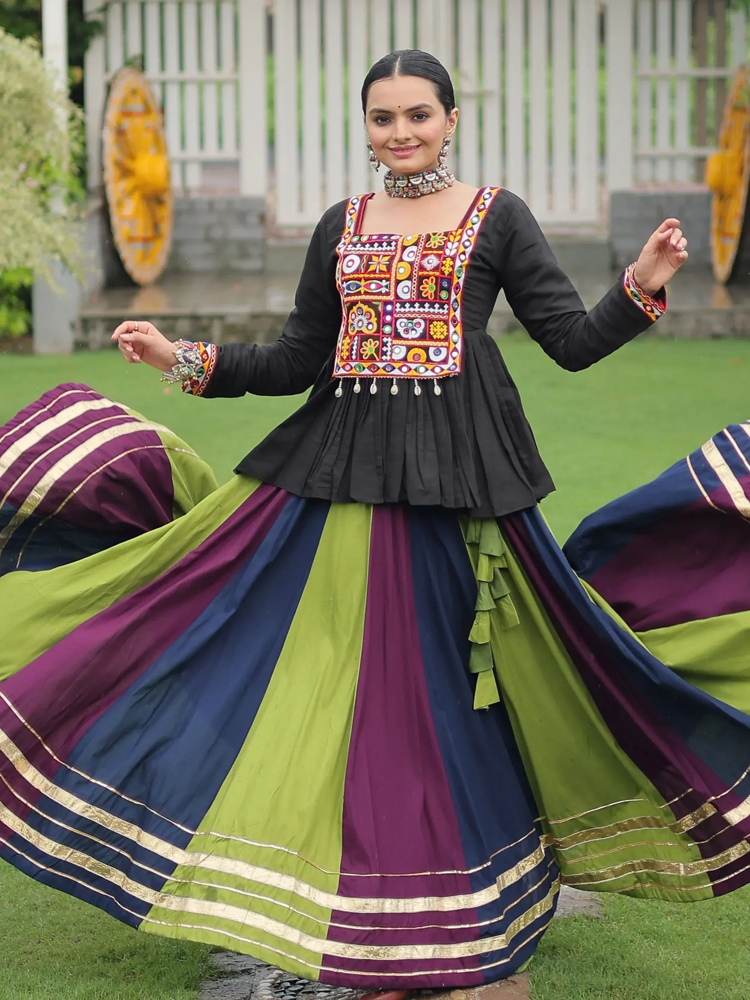Woman in colorful embroidered ethnic gown with pleated skirt, dancing outdoors
