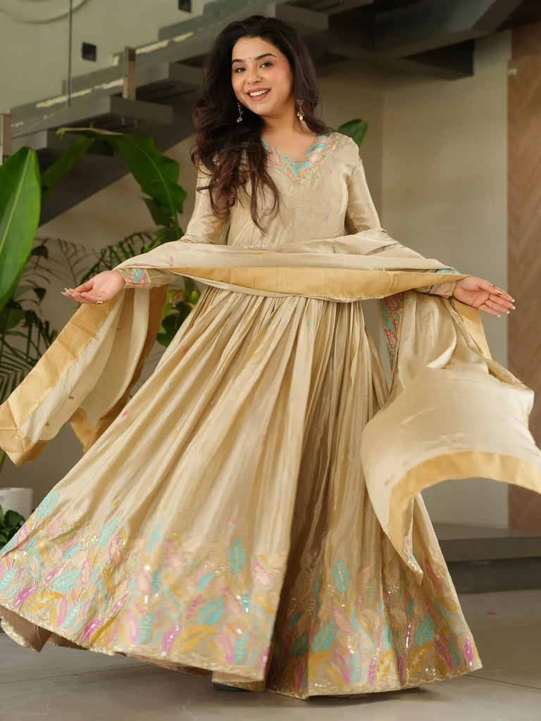Woman in elegant beige ethnic gown with colorful embroidery, perfect for Indian celebrations