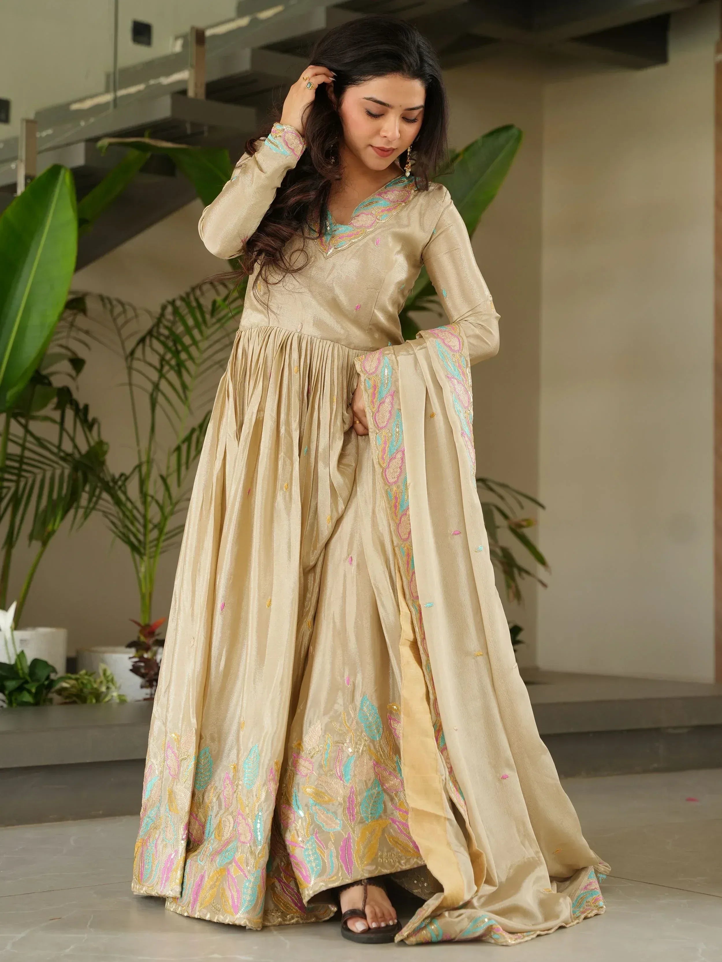 Beige embroidered ethnic gown with colorful floral motifs, perfect for Indian festive occasions