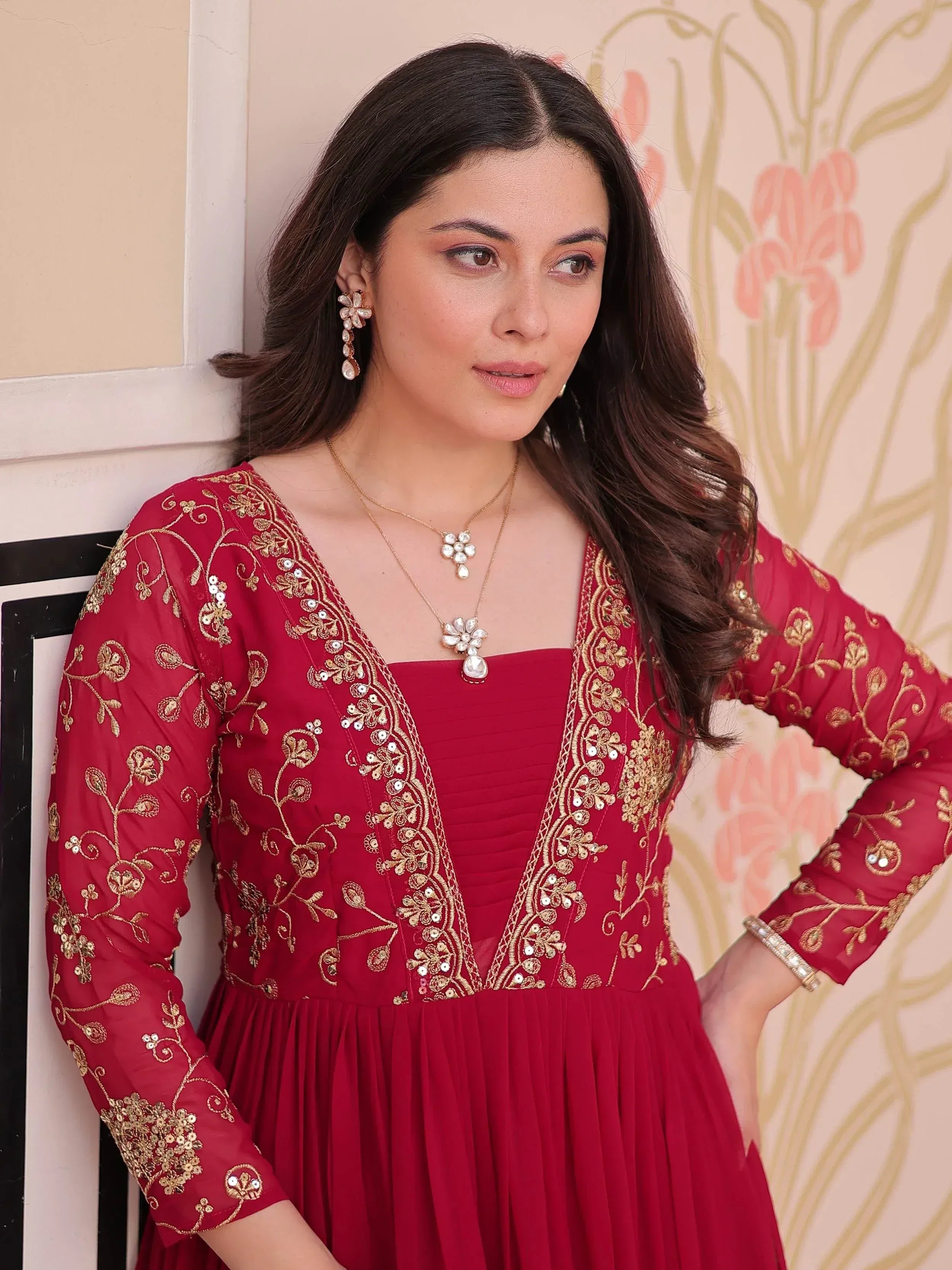 Red ethnic gown with gold embroidery and floral jewelry for festive occasions