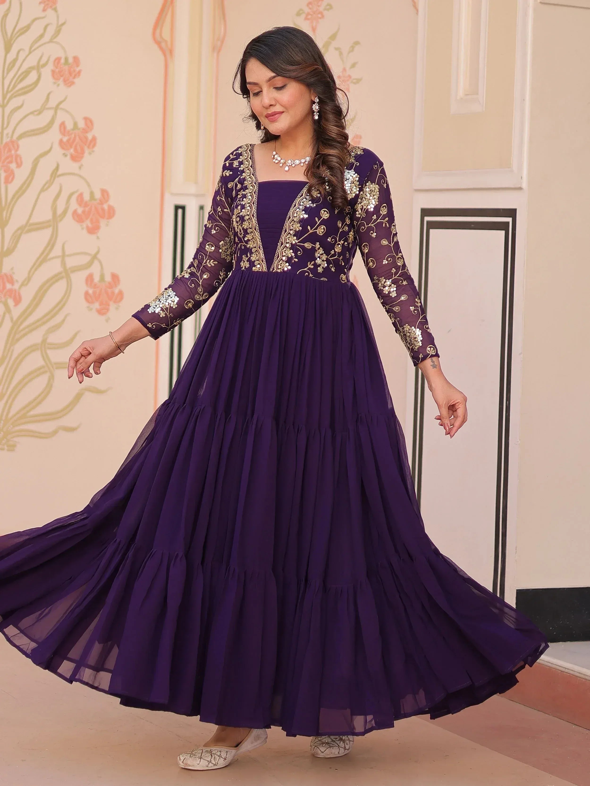 Purple ethnic gown with gold embroidery, pleated skirt, and sheer sleeves for festive occasions