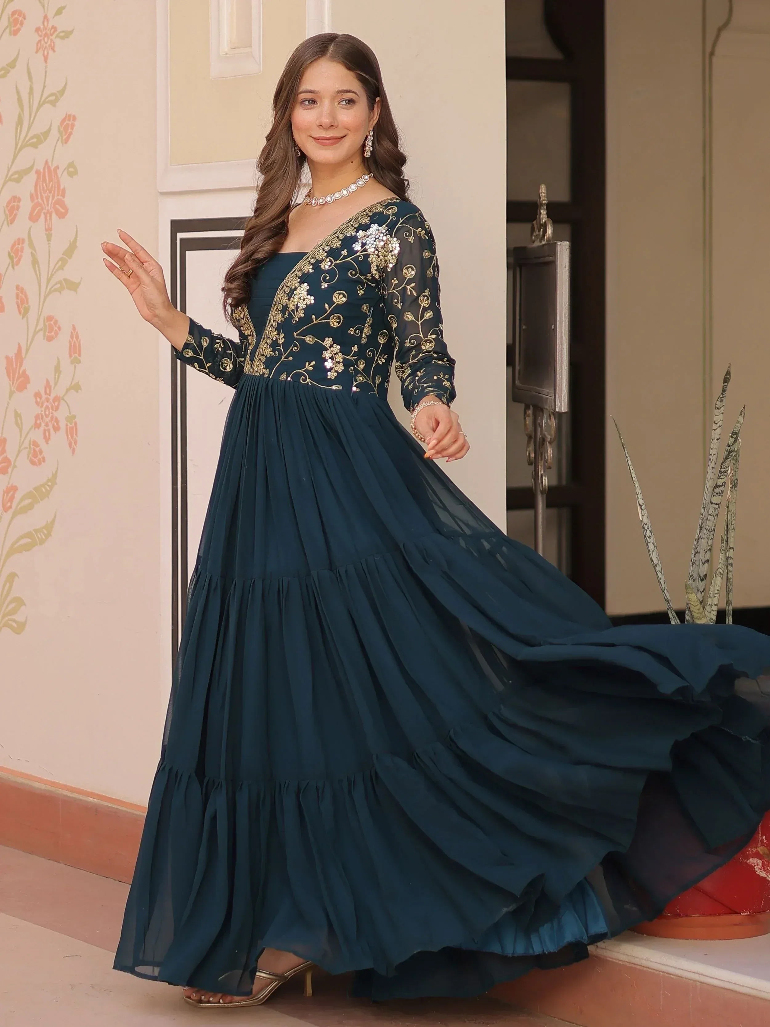 Elegant teal ethnic gown with gold embroidery and layered skirt, perfect for Indian occasions.