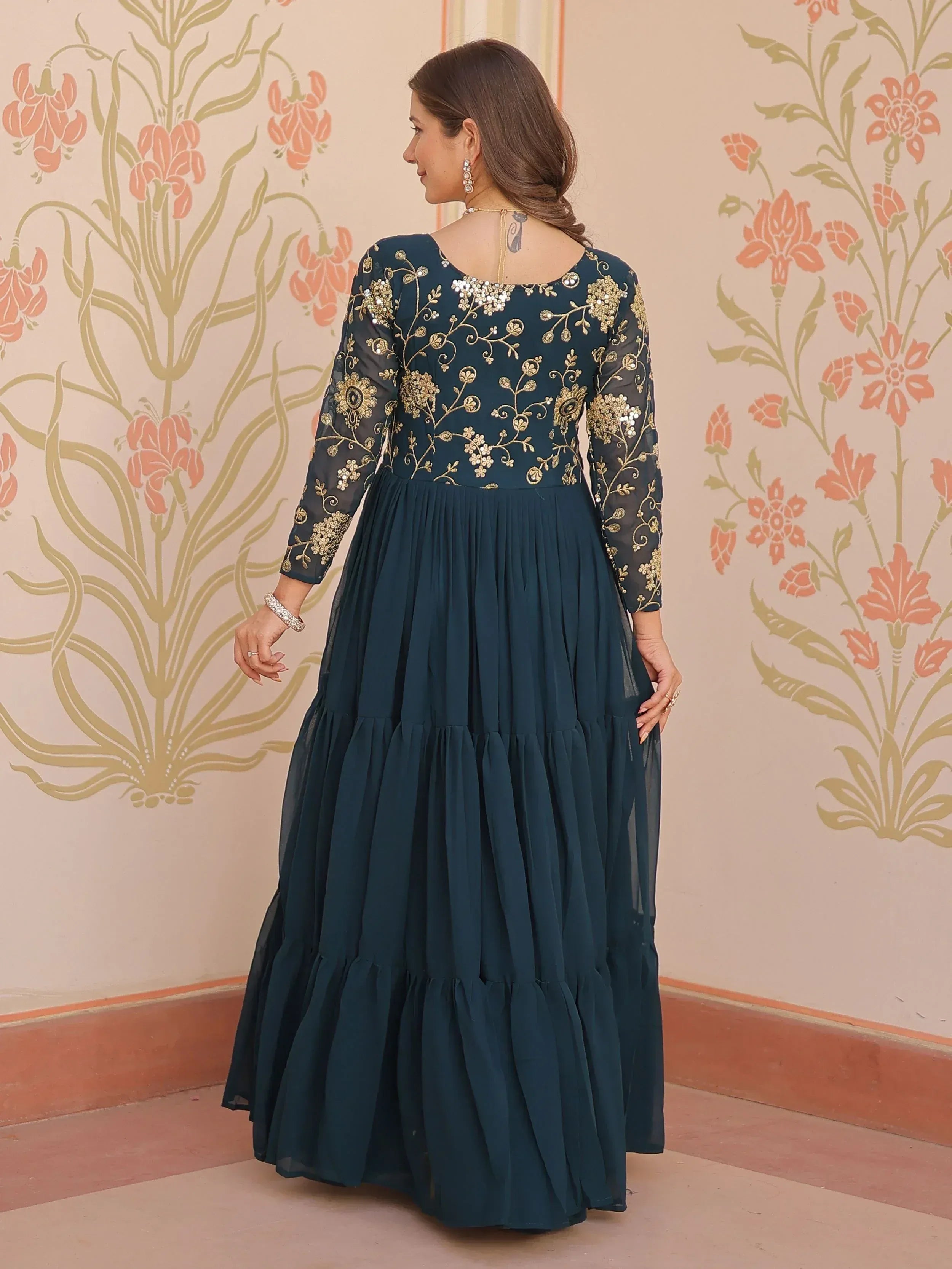 Teal ethnic gown with gold floral embroidery and sheer sleeves, perfect for Indian occasions.