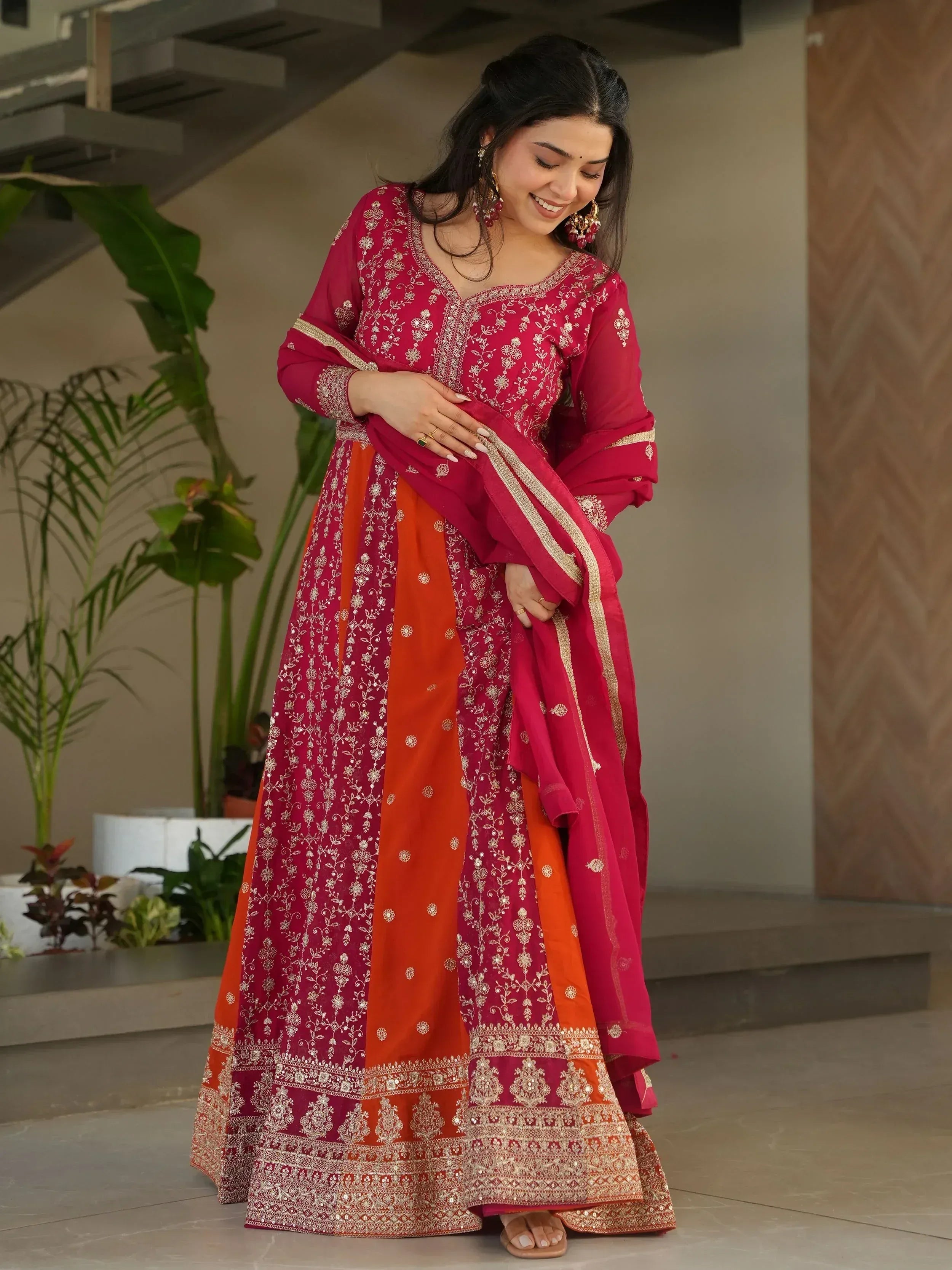 Woman in red and orange embroidered Indian anarkali suit with gold detailing, perfect for festive occasions
