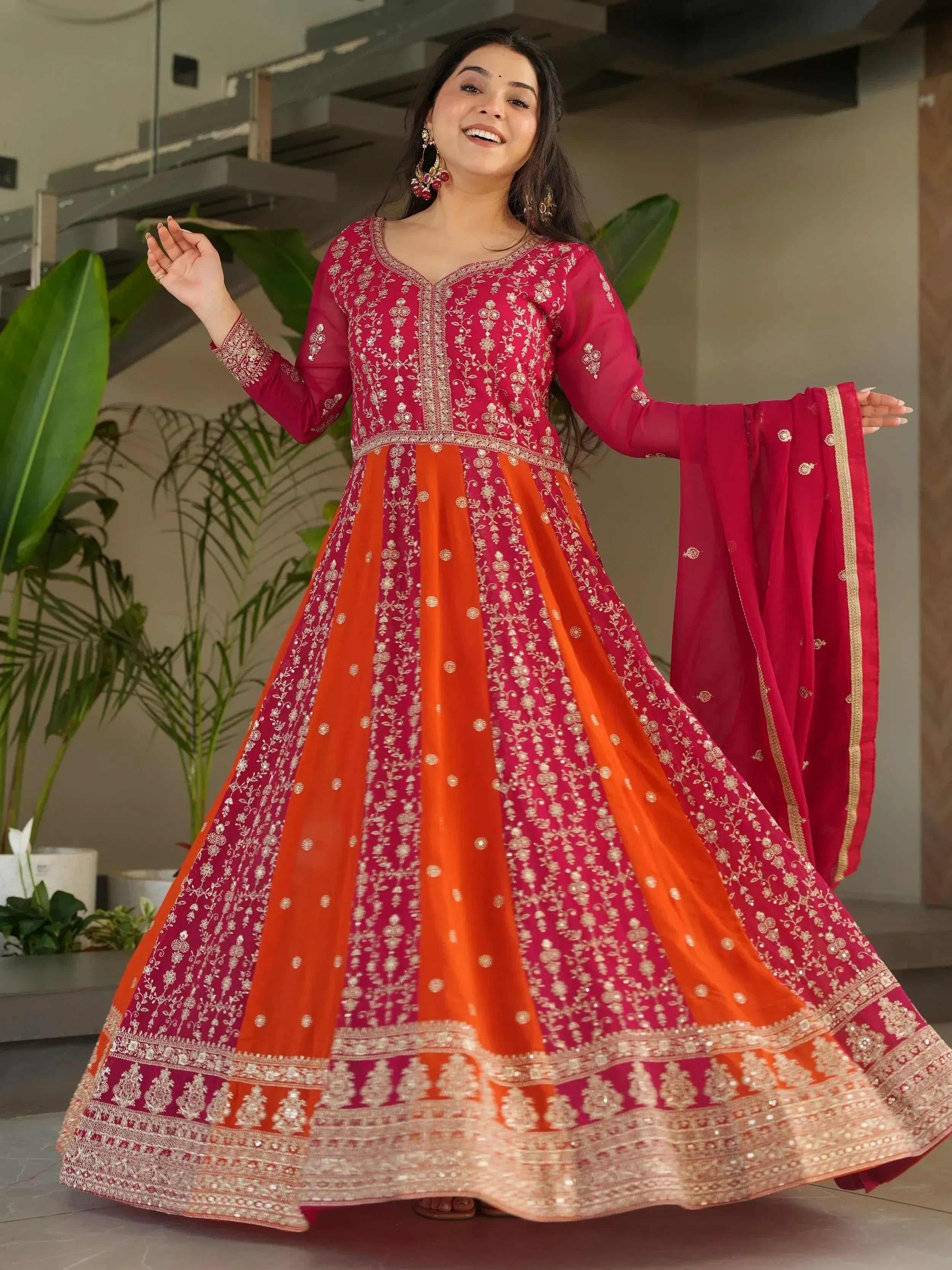 Woman in red and orange embroidered anarkali suit with gold detailing, perfect for Indian ethnic wear occasions.