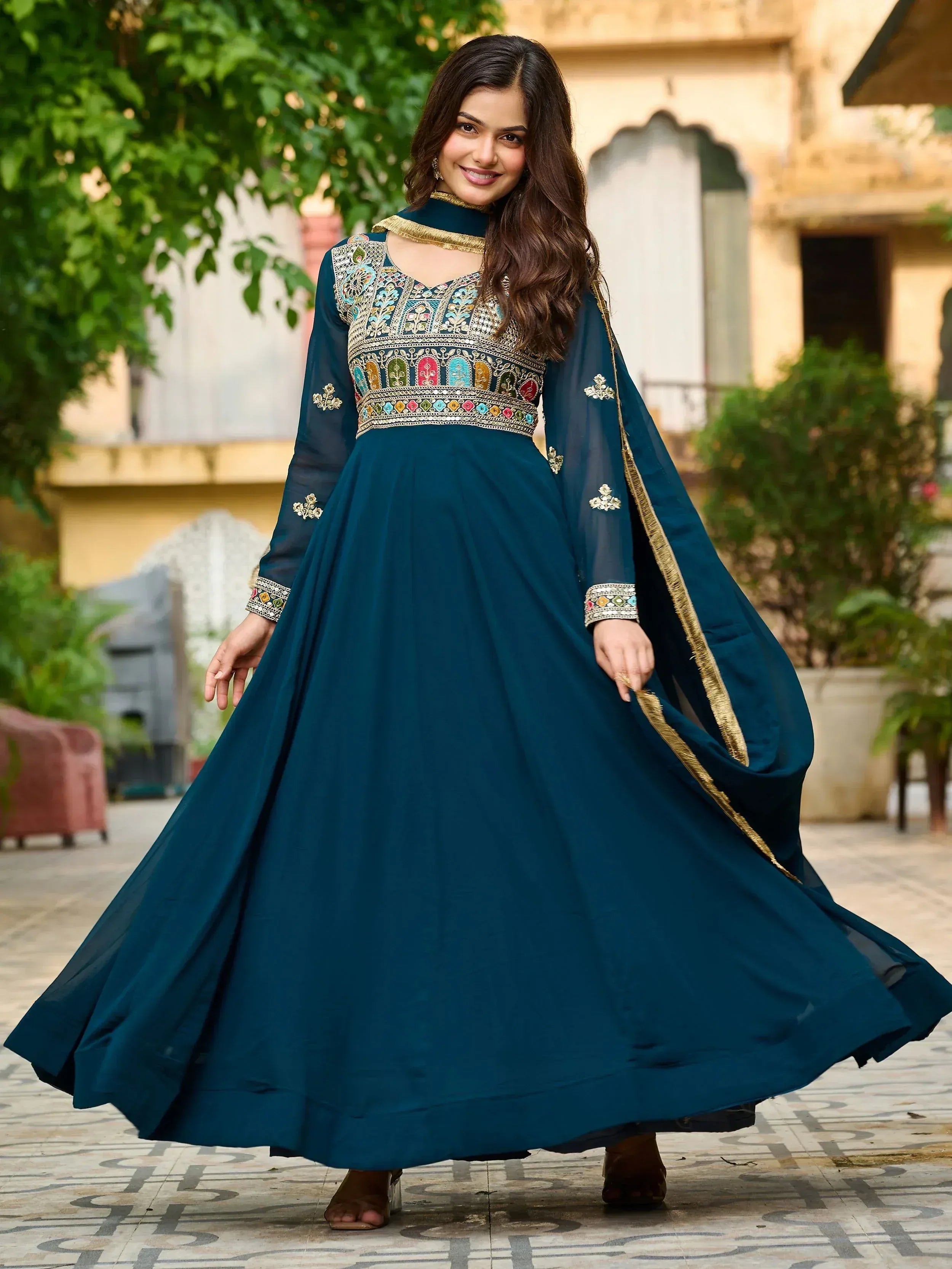 Elegant teal anarkali gown with intricate embroidery and gold trim, perfect for festive occasions.