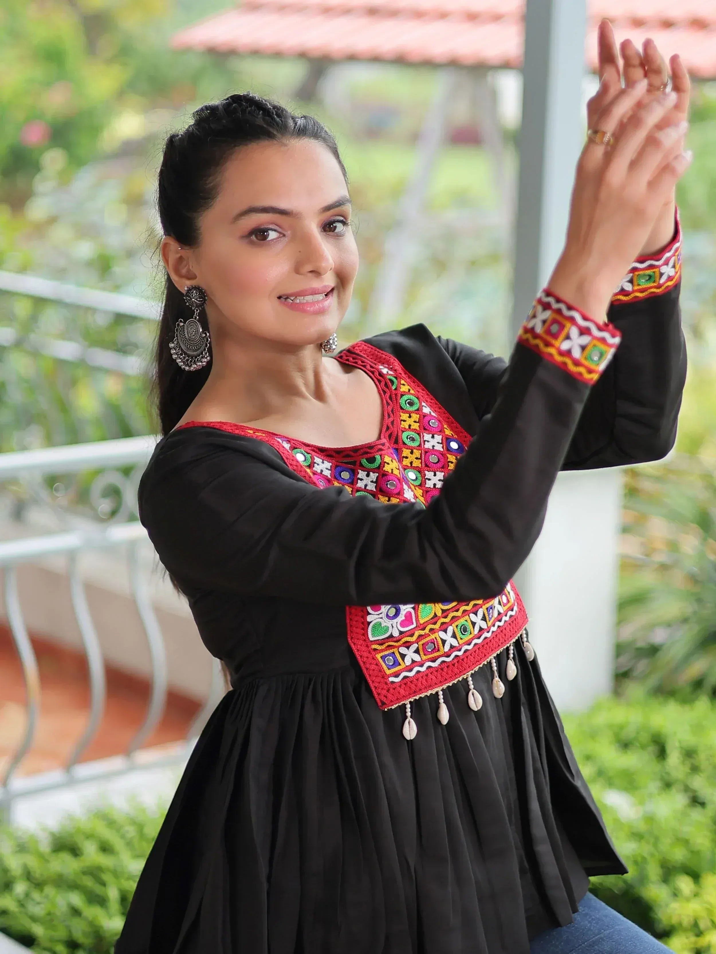 Black ethnic gown with colorful mirror embroidery and shell tassels, perfect for Indian festive wear
