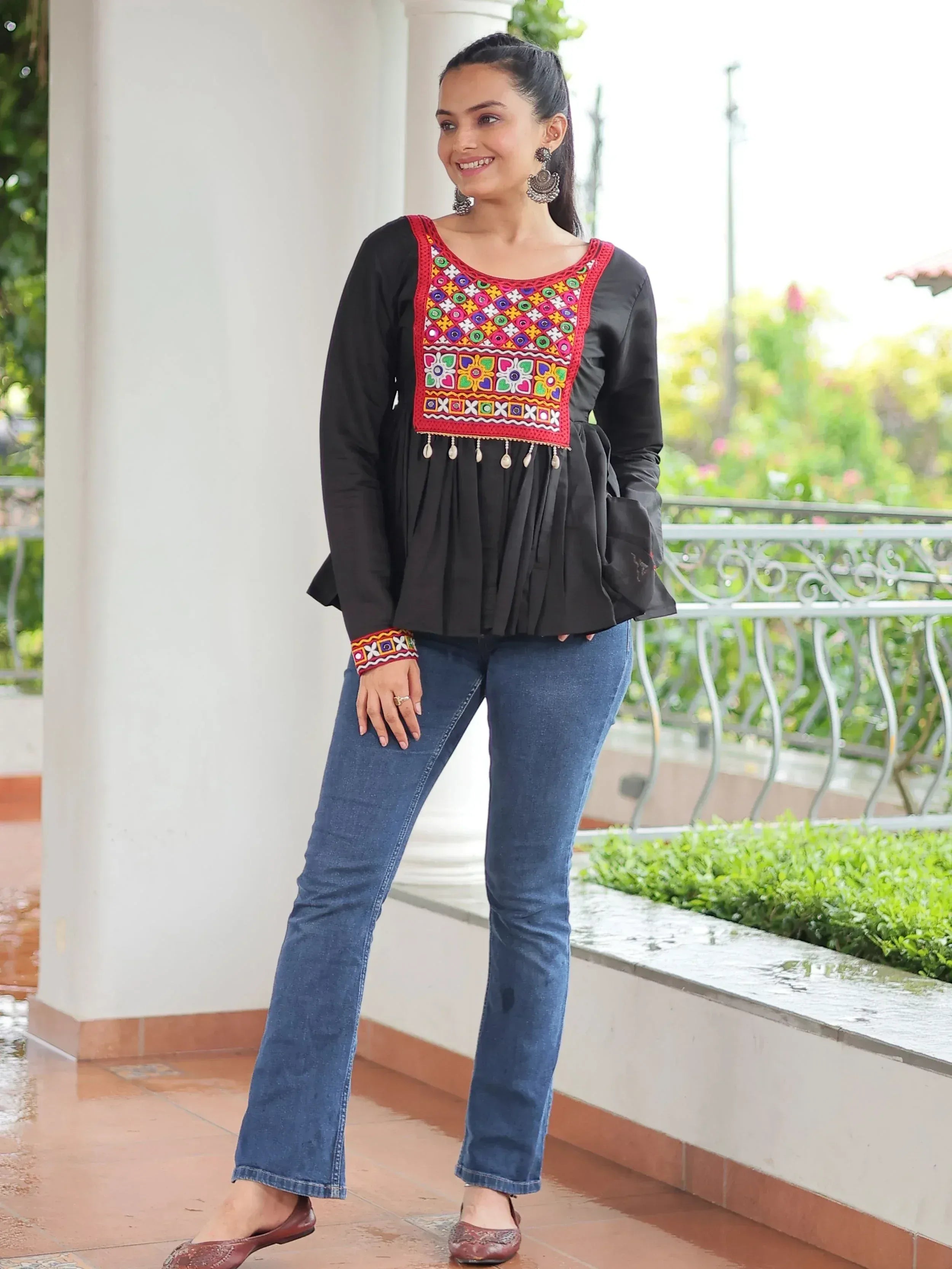 Black embroidered top with colorful patterns paired with blue jeans, ideal for ethnic fashion.