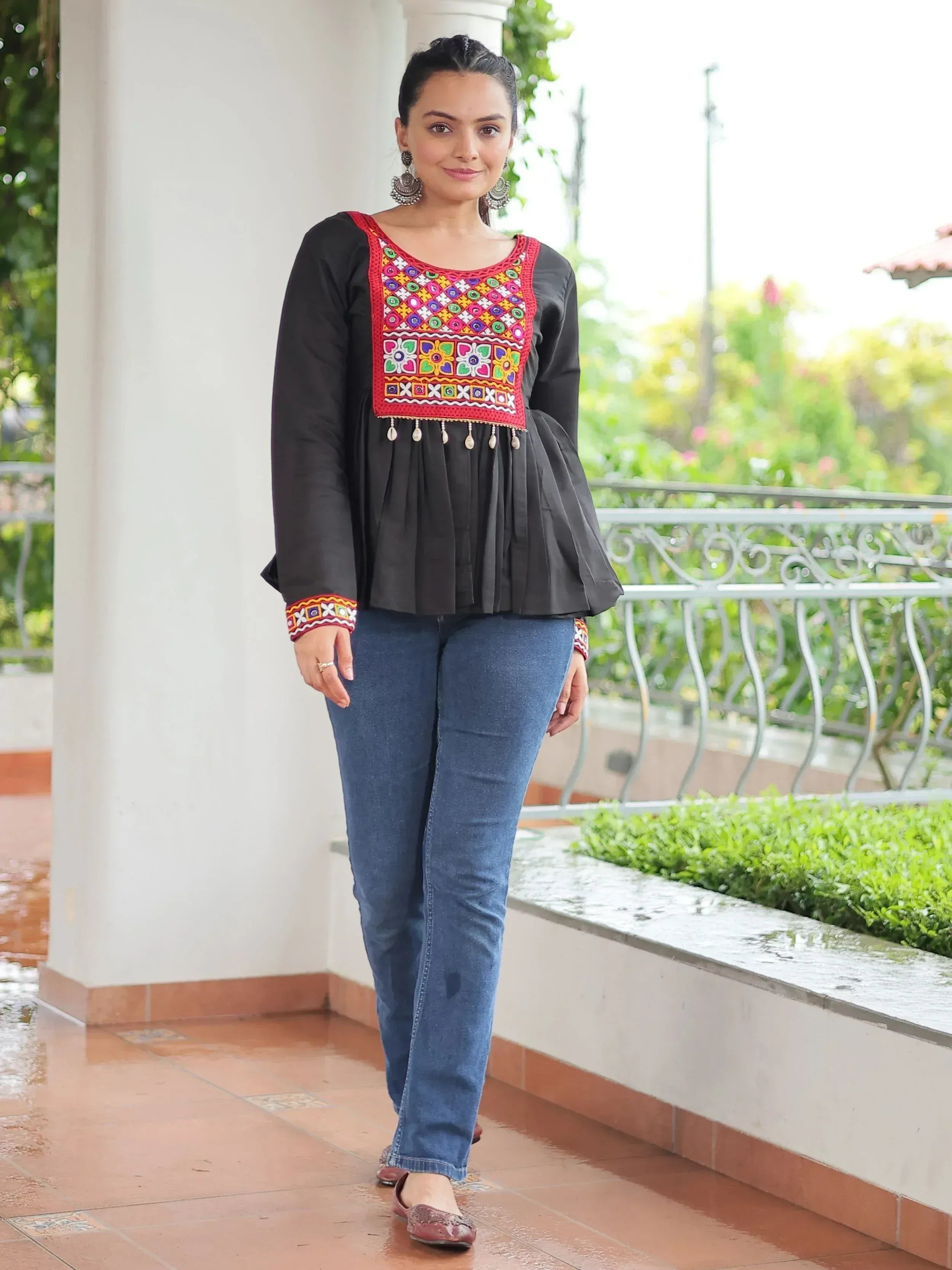 Black ethnic top with colorful mirror work and embroidery, paired with jeans, perfect for casual Indian wear.