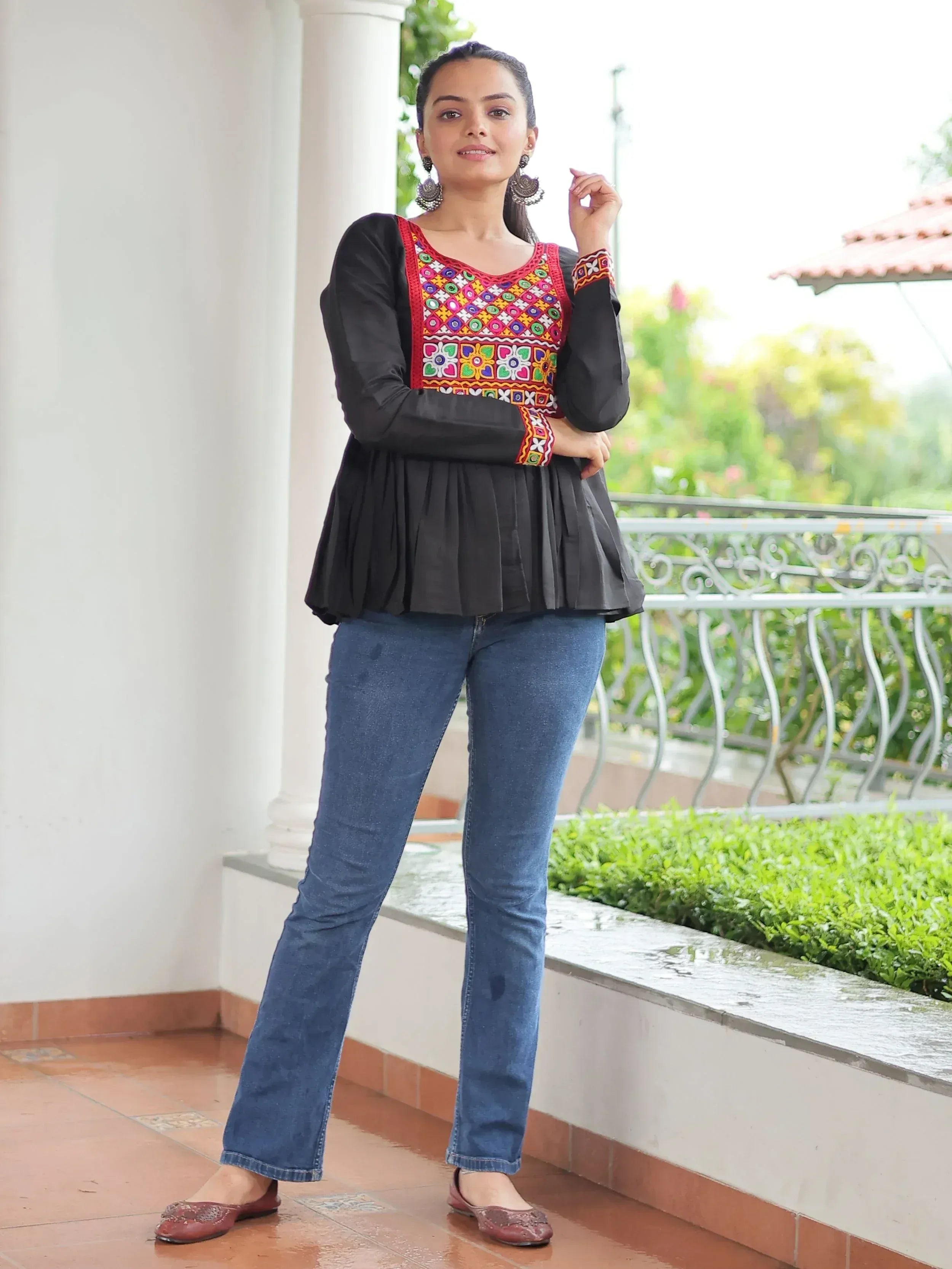 Black peplum top with colorful embroidery, paired with blue jeans and ethnic flats for casual ethnic wear