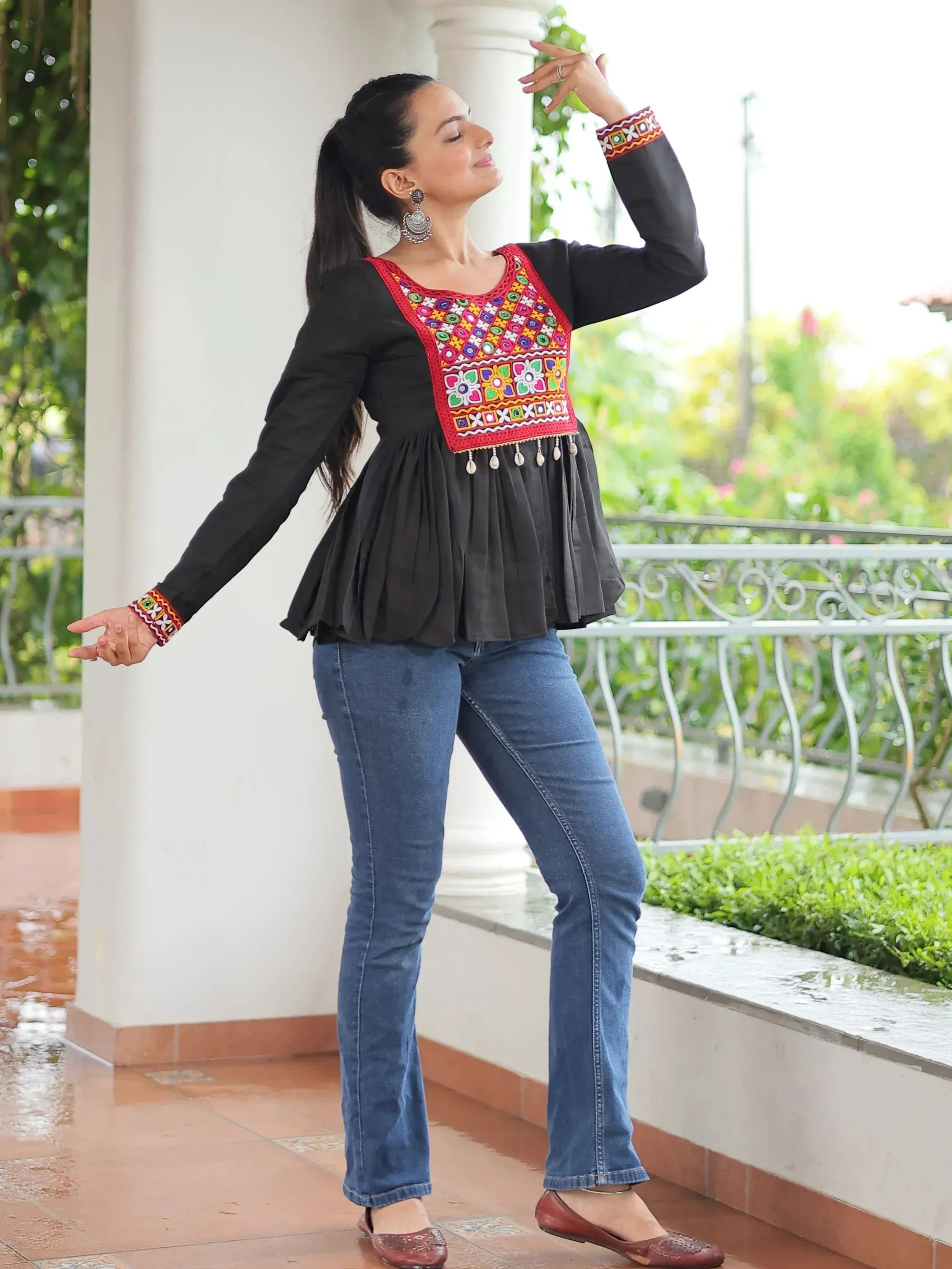 Black ethnic top with colorful mirror work and embroidery, paired with blue jeans, perfect for casual Indian wear.