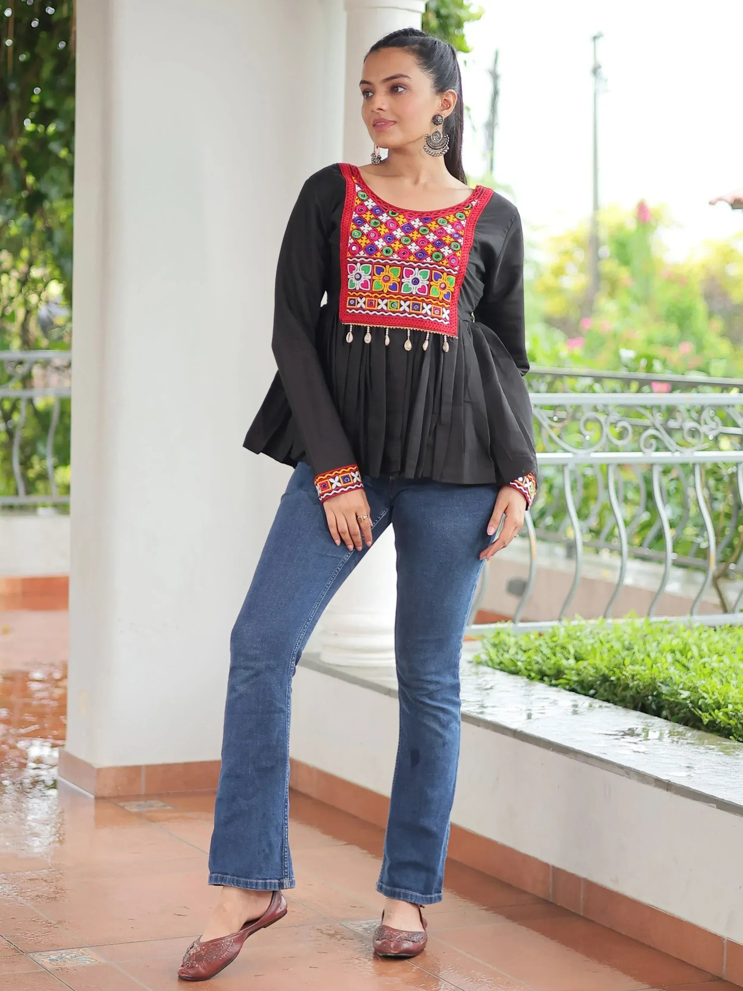 Black ethnic top with colorful mirror work, paired with blue jeans and jutti flats, perfect for casual Indian wear.