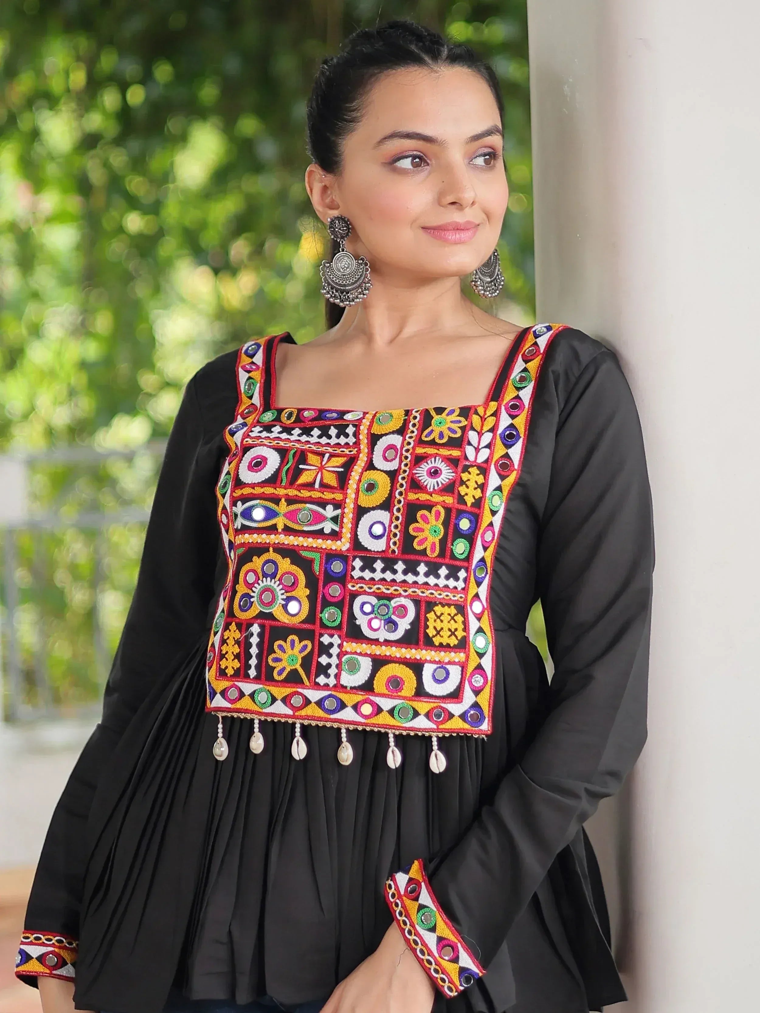 Black ethnic kurti with colorful mirror embroidery and tassels, paired with statement earrings