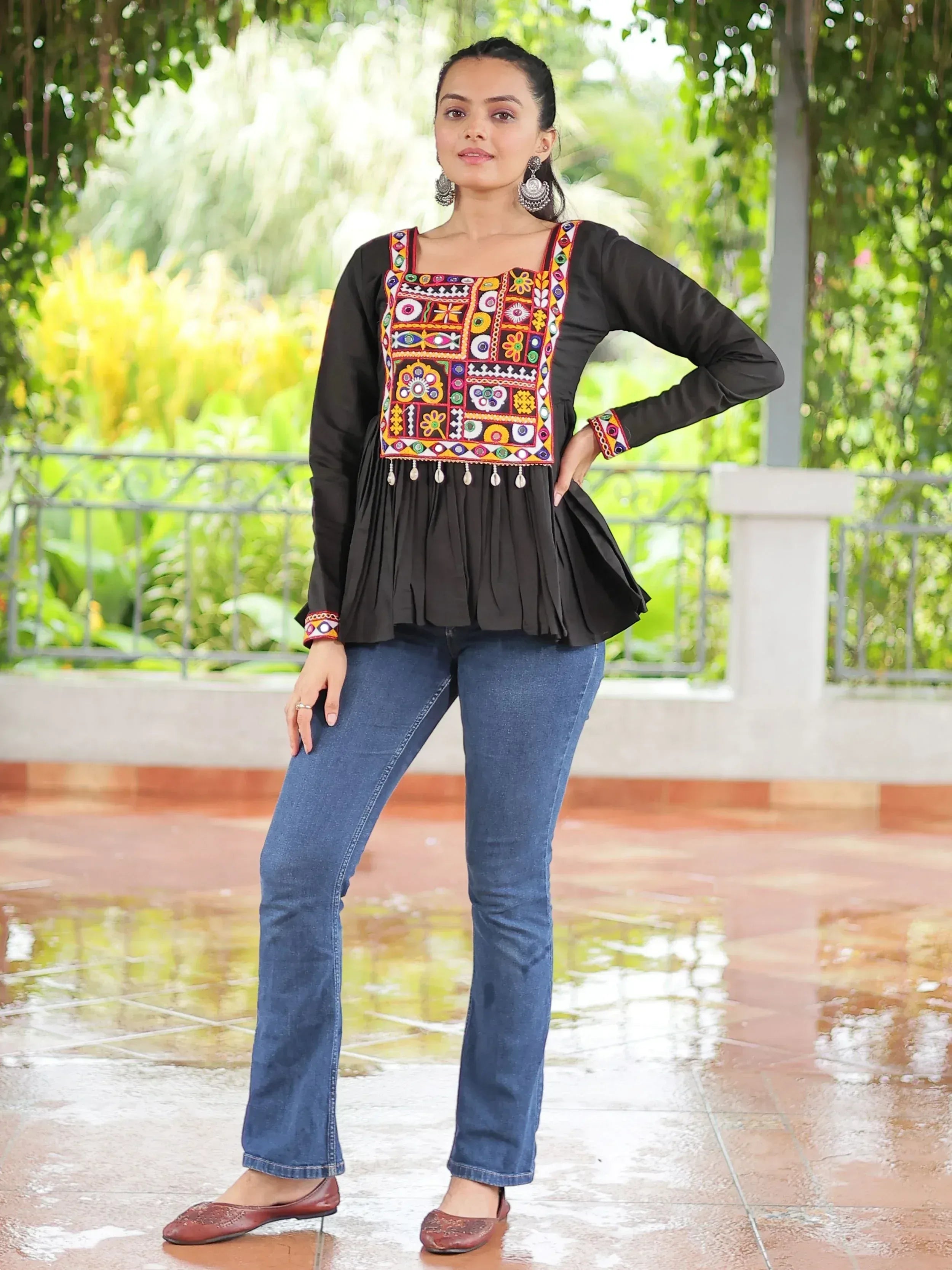 Black ethnic top with colorful mirror work and embroidery, paired with blue jeans and juttis