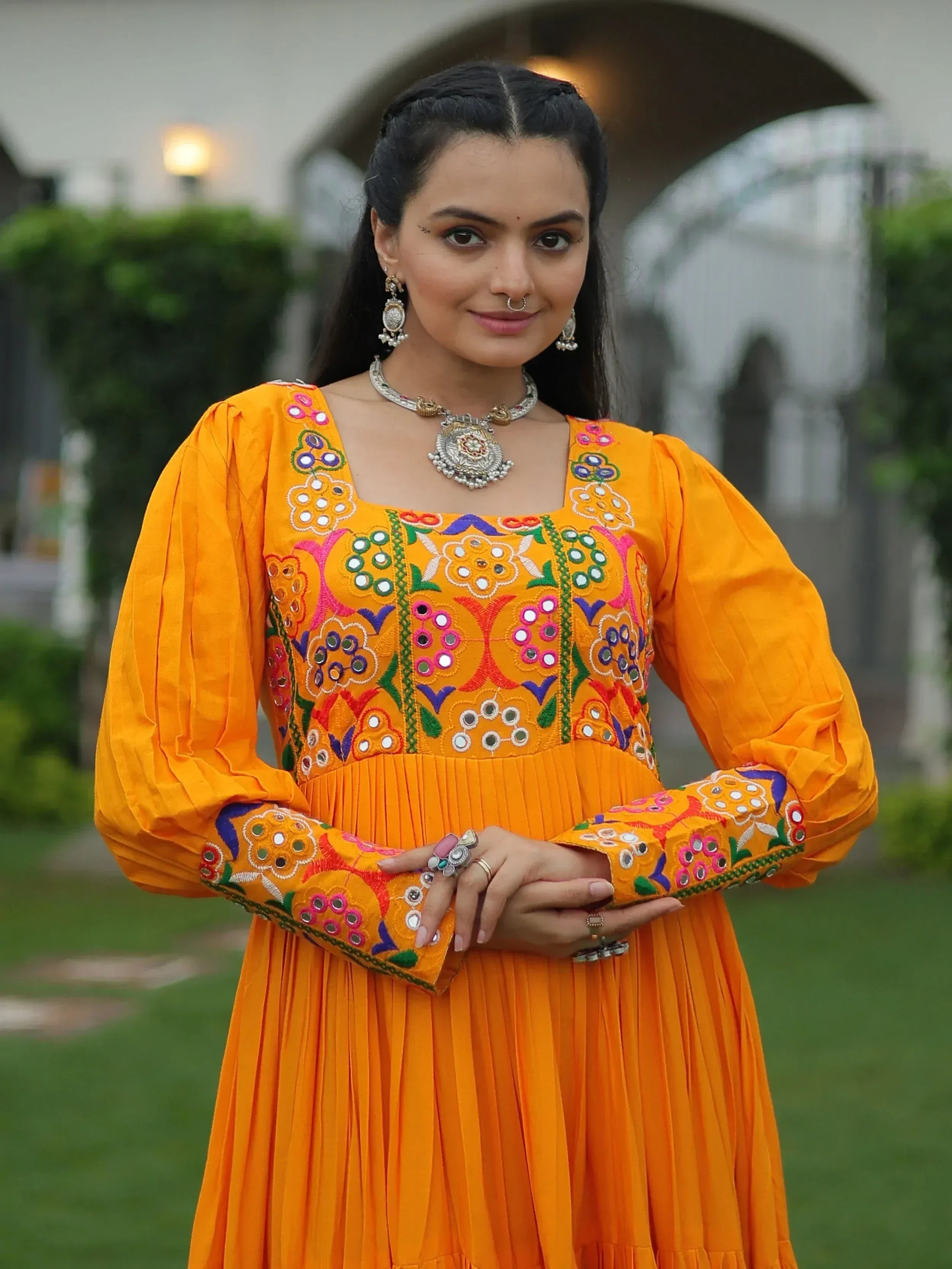 Vibrant orange ethnic gown with colorful mirror embroidery, perfect for Indian celebrations and festive occasions.