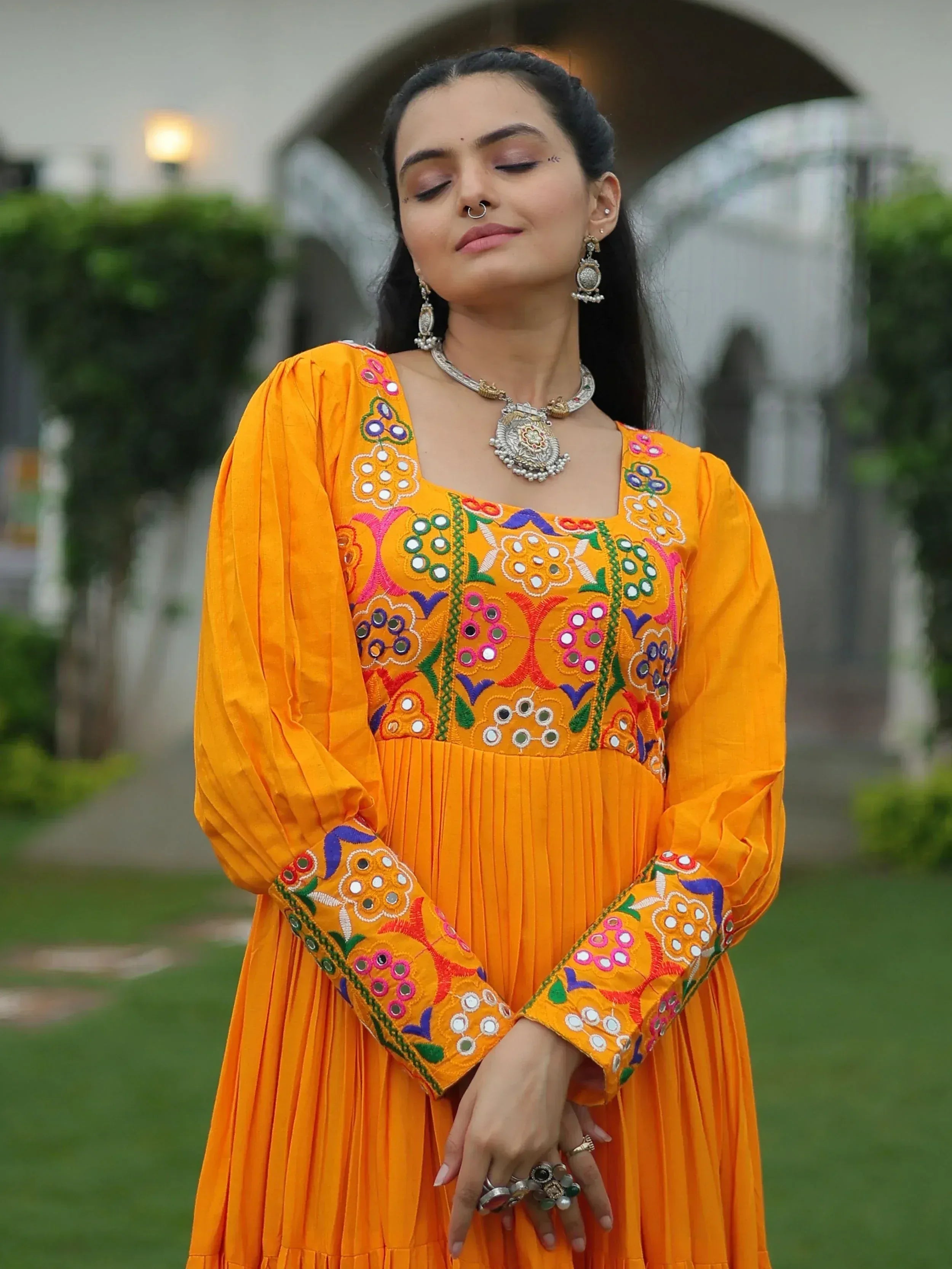 Vibrant orange ethnic gown with mirror work embroidery, perfect for Indian festive occasions and celebrations.