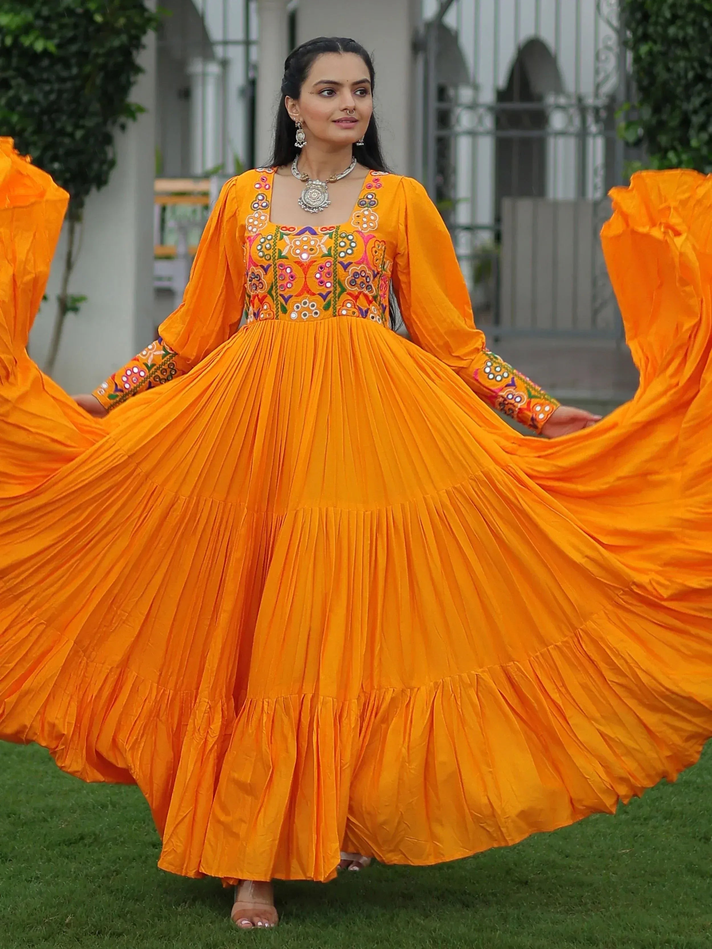 Vibrant orange ethnic gown with floral embroidery, pleated skirt, and puff sleeves for festive occasions