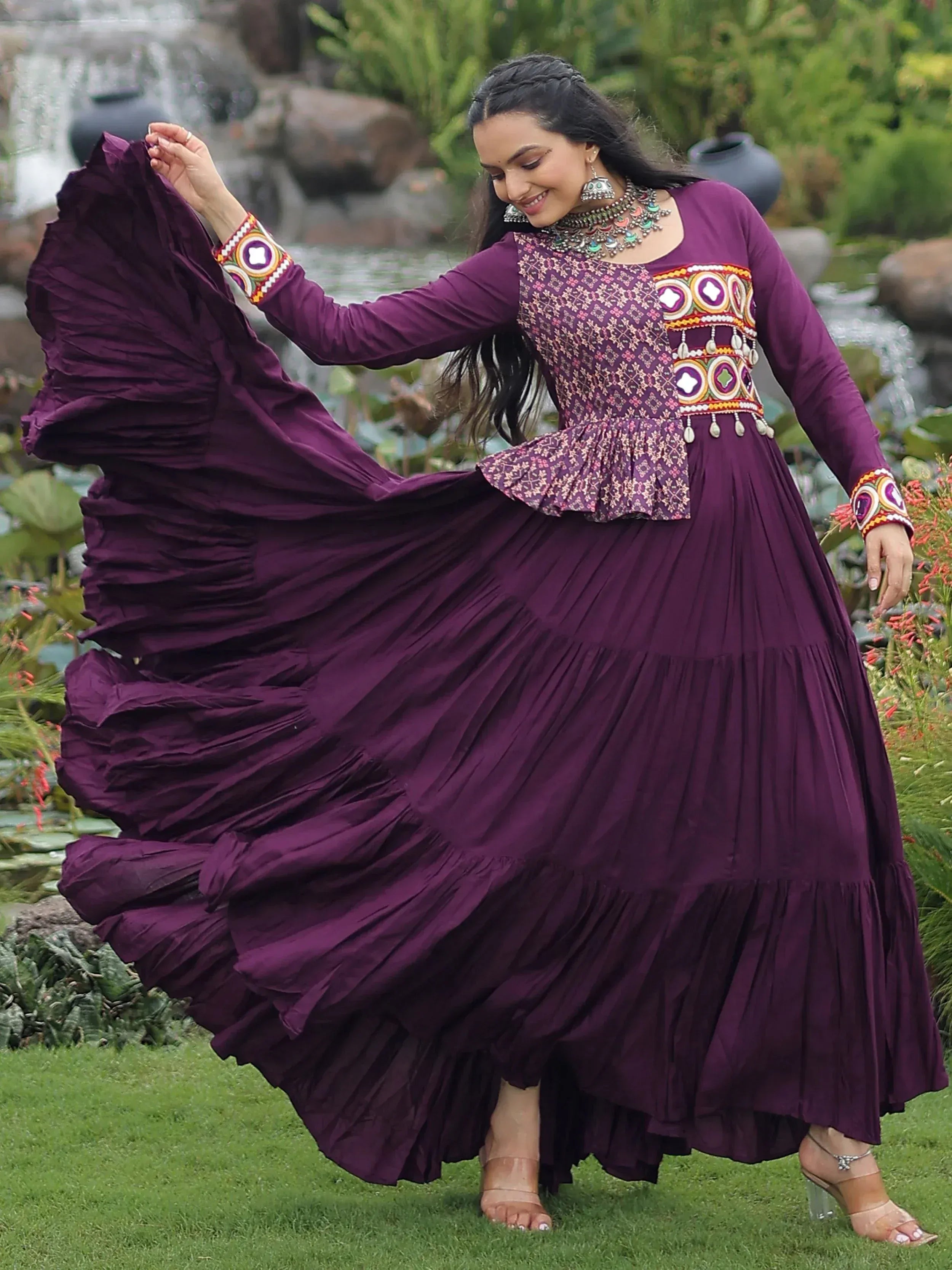 Woman twirling in purple ethnic gown with embroidered blouse, perfect for festive occasions and Indian wear.