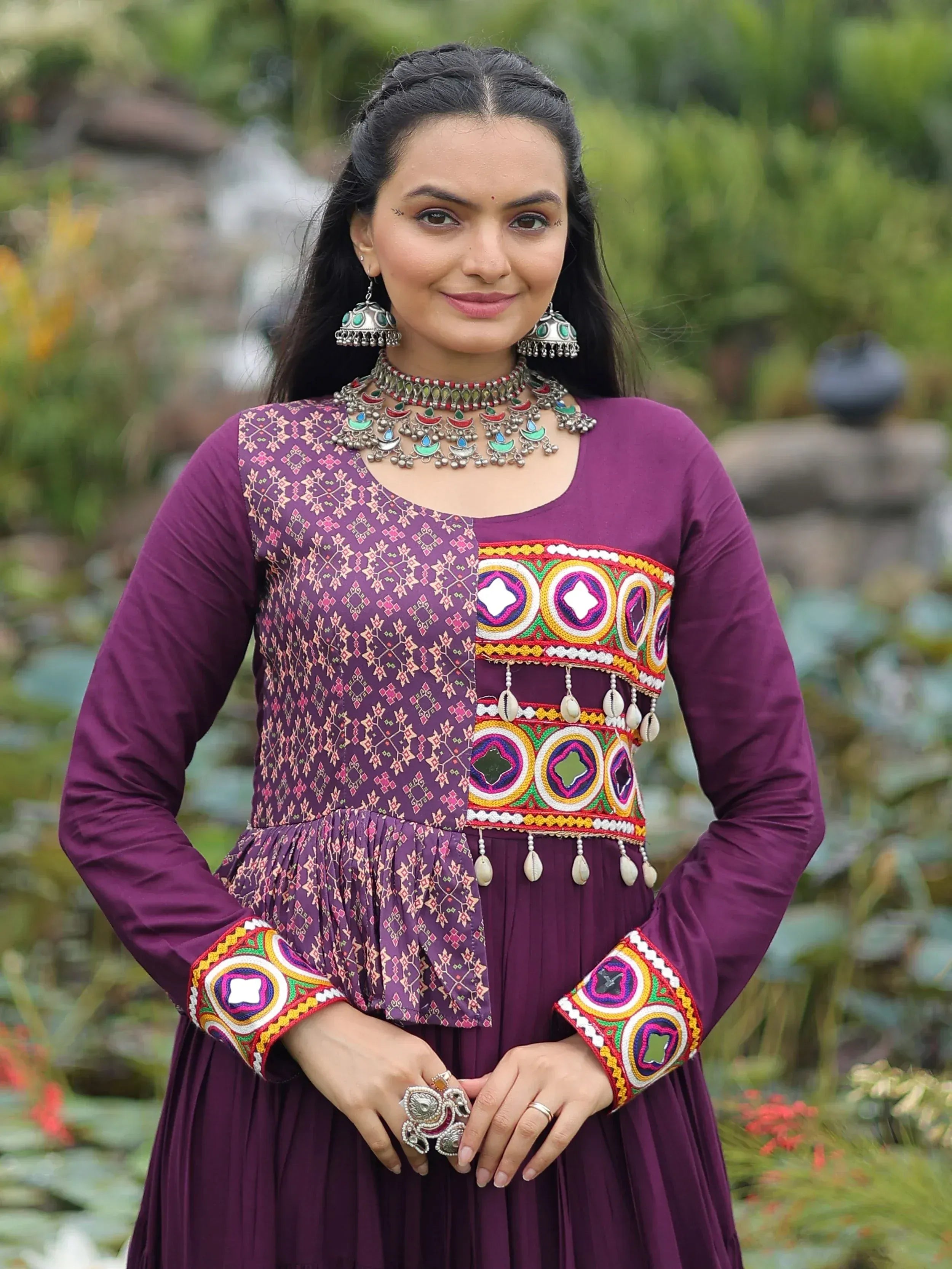 Purple ethnic gown with colorful embroidery and mirror work, paired with traditional jewelry