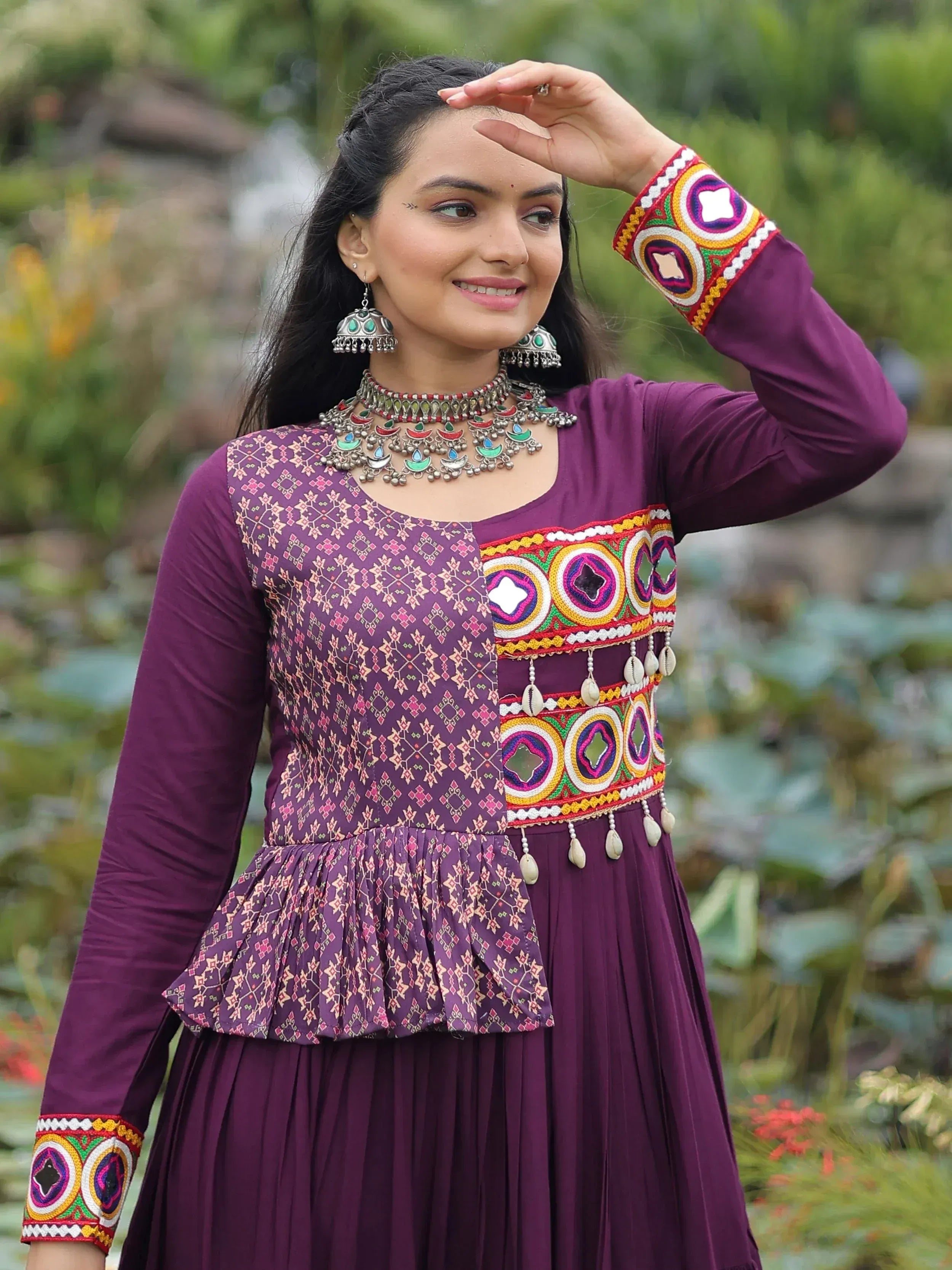 Purple ethnic gown with mirror work, embroidery, and traditional jewelry for Indian wear