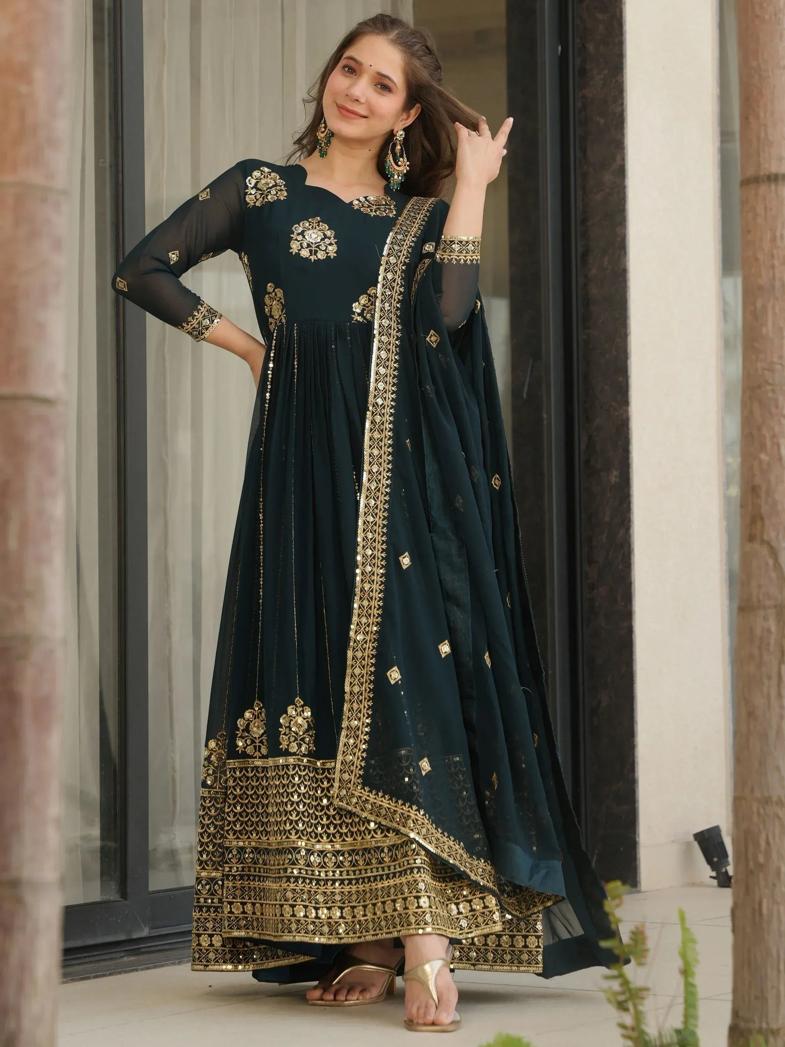 Elegant dark green ethnic gown with gold embroidery and sequins, perfect for Indian festive occasions.