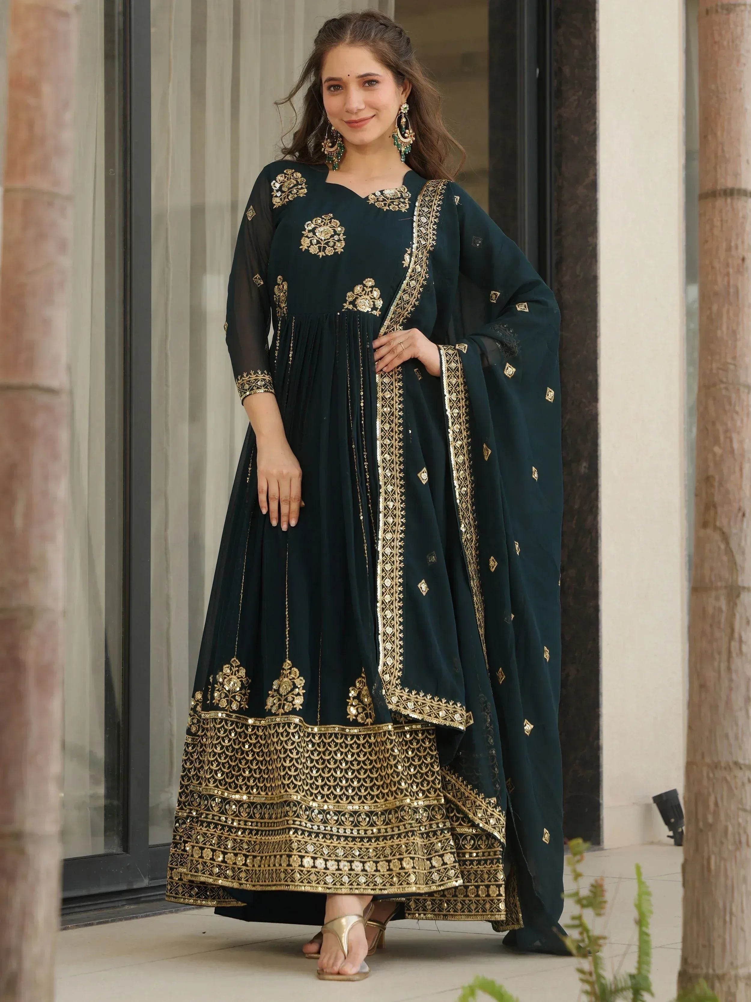 Dark green ethnic Anarkali suit with gold embroidery and matching dupatta, perfect for Indian festive occasions.