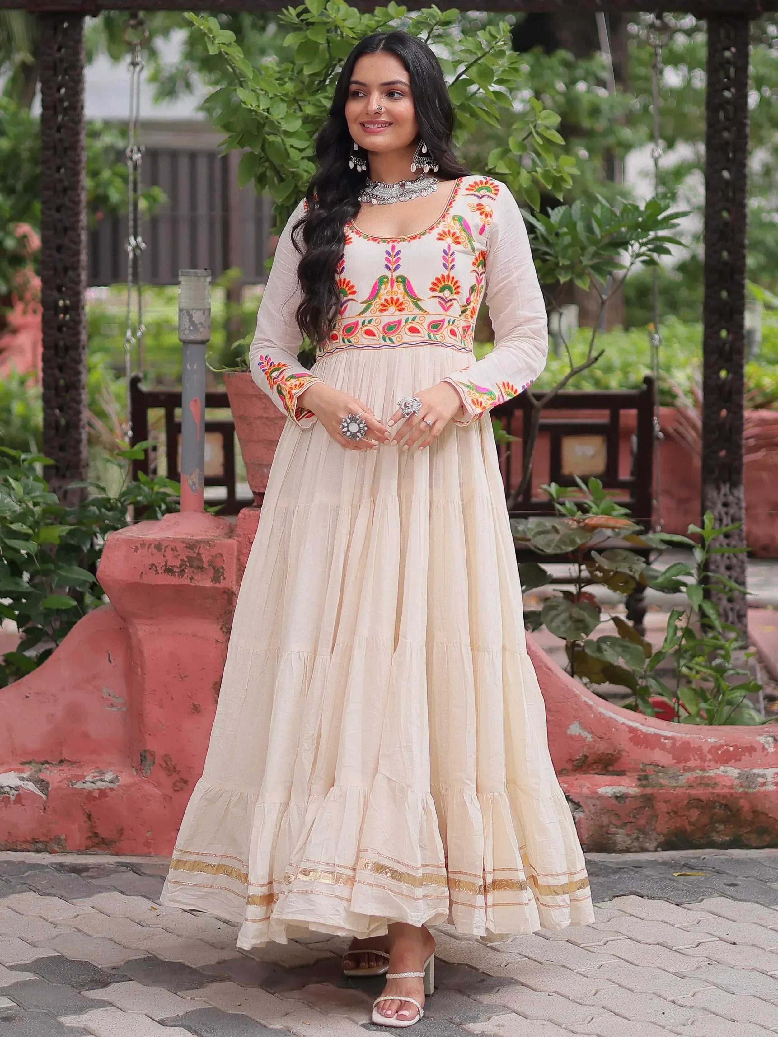 Cream embroidered ethnic gown with colorful floral and bird motifs, perfect for Indian occasions.