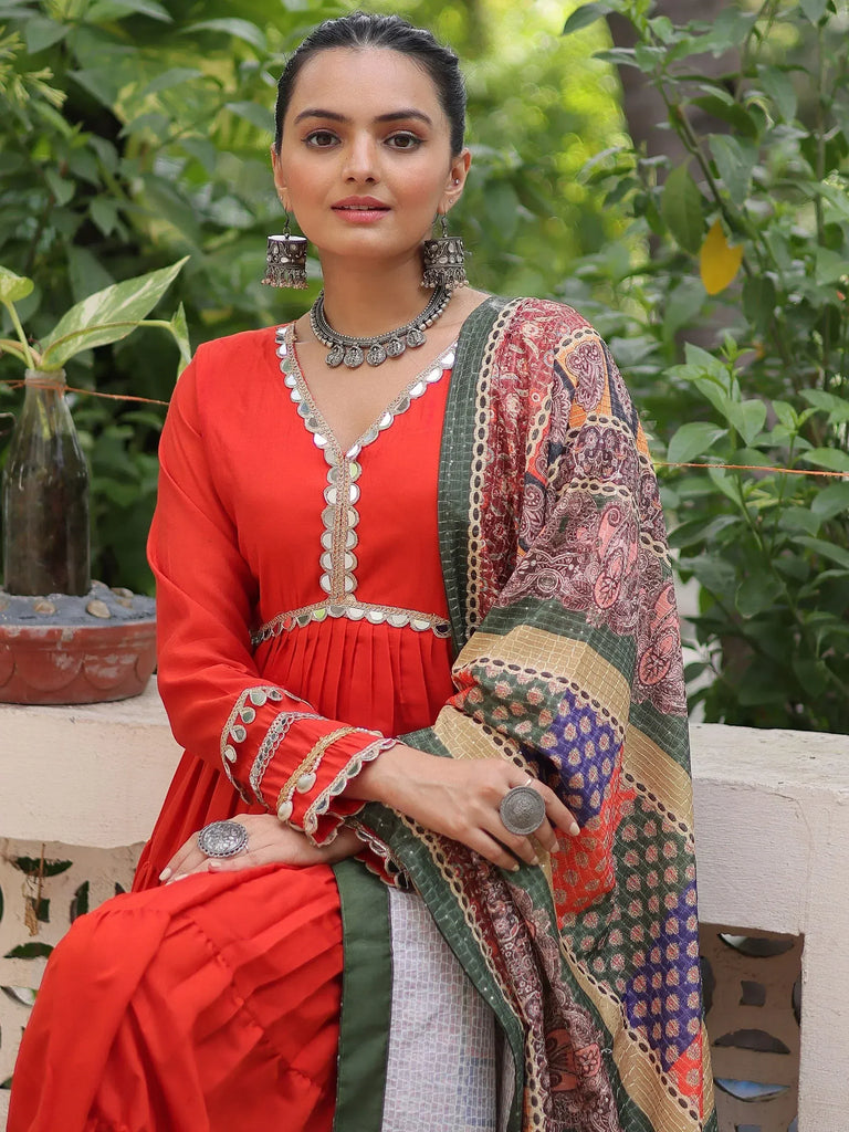 Red ethnic gown with mirror work and printed dupatta, styled with traditional jewelry
