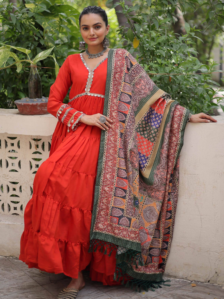 Vibrant red tiered ethnic gown with intricate embroidery and colorful patchwork dupatta