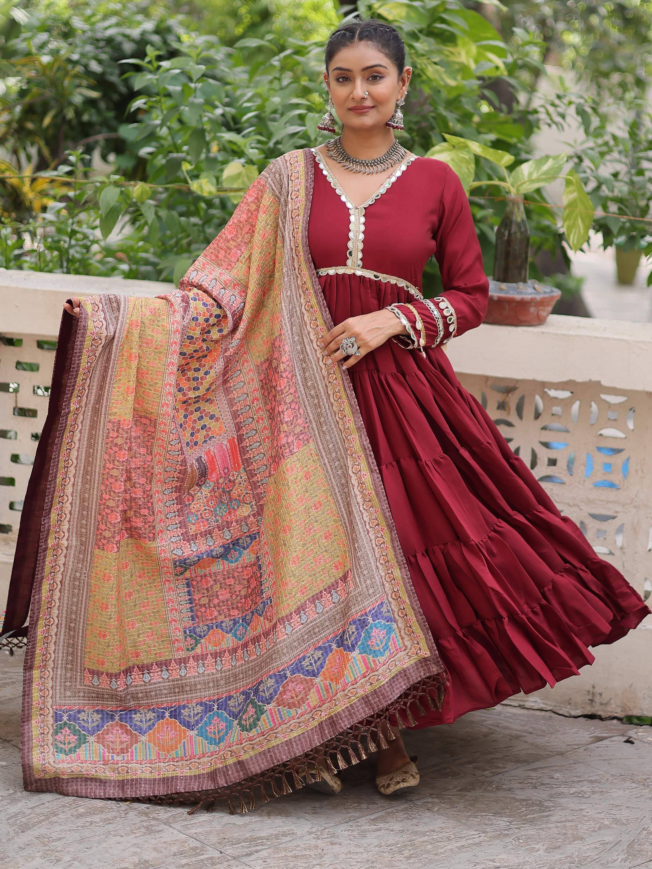 Maroon tiered ethnic gown with mirror work and printed dupatta, perfect for festive occasions