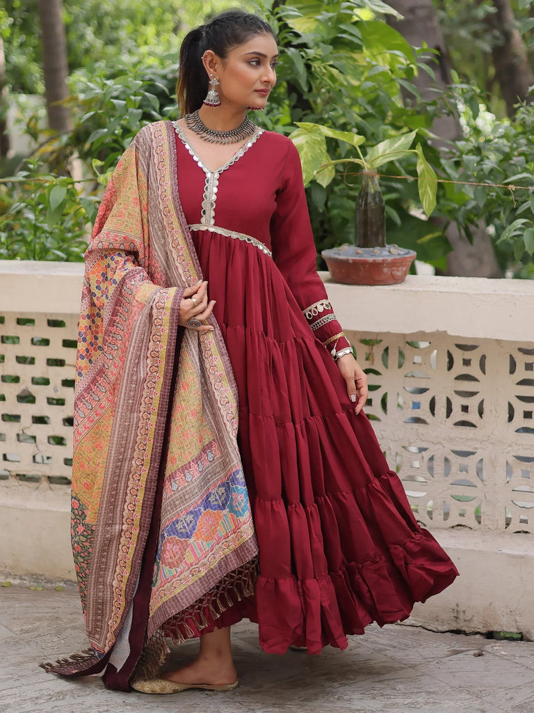 Maroon tiered ethnic gown with mirror work and printed dupatta, perfect for Indian festive occasions